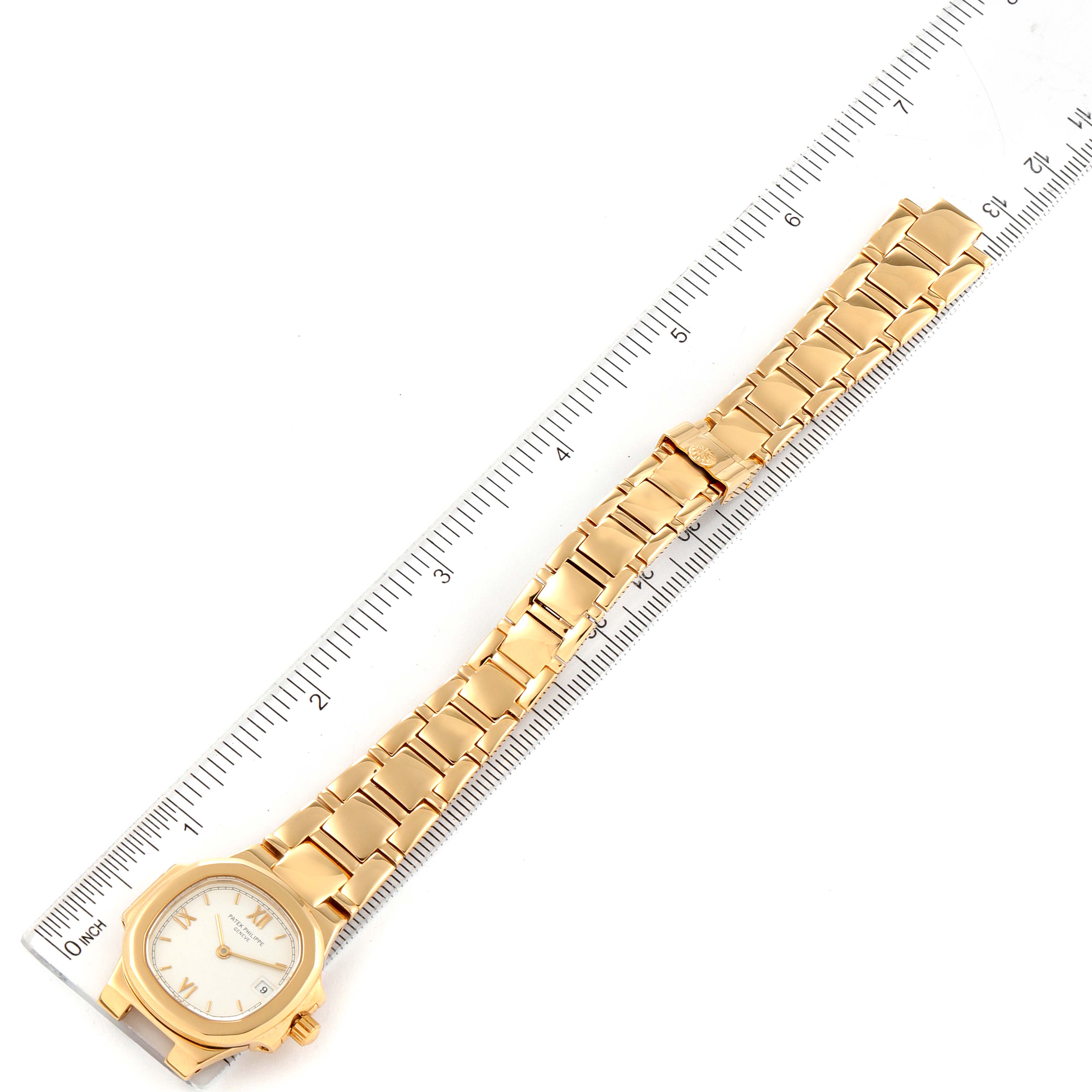 The image shows a gold Patek Philippe Nautilus 4700/51 Women's Yellow Gold White Dial 4700/51 Women's Yellow Gold White Dial watch placed alongside a ruler, showcasing its face and full bracelet.