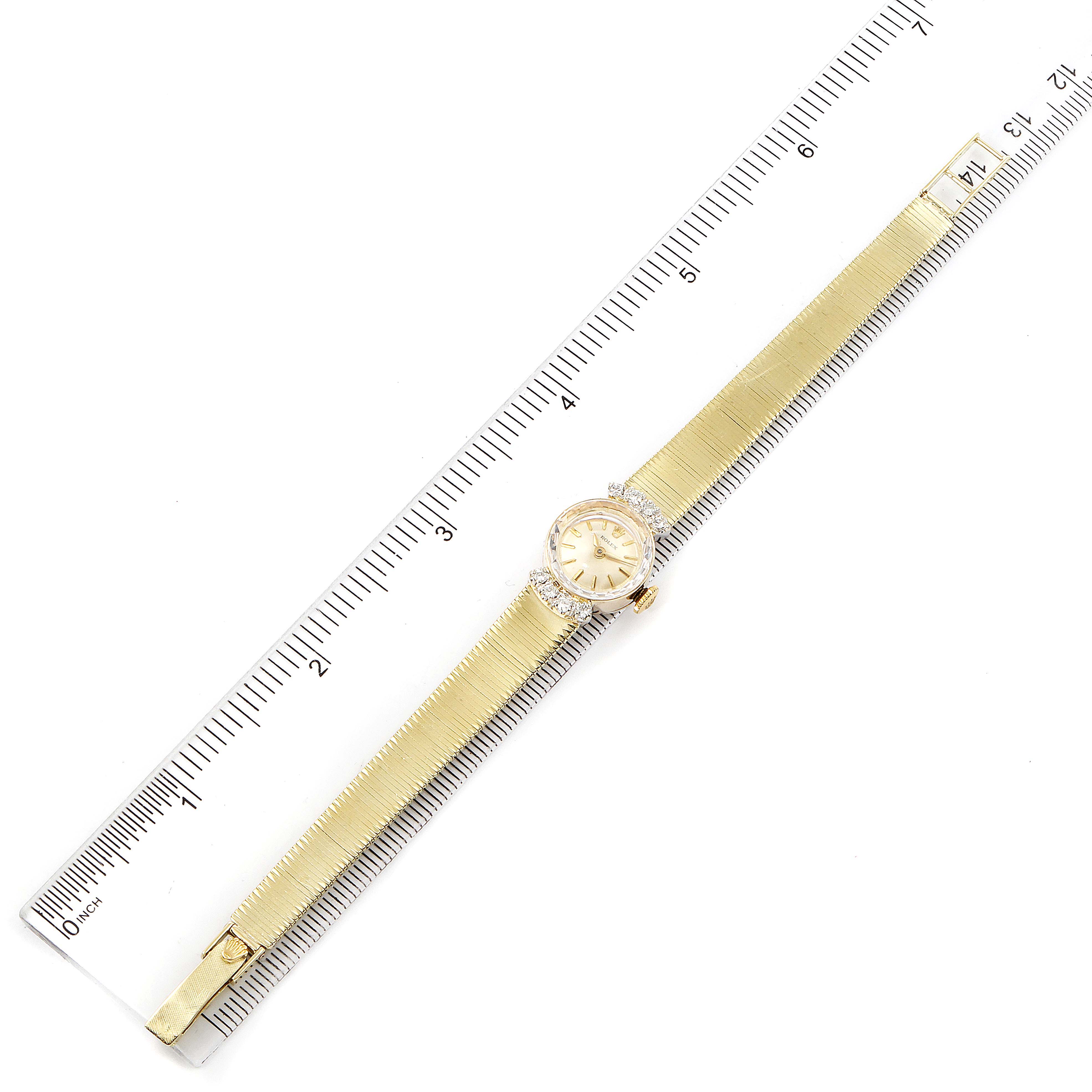 The image shows the full length of a gold Rolex Cocktail  Women's Yellow Gold Silver Dial  Women's Yellow Gold Silver Dial model watch placed alongside a ruler for scale.