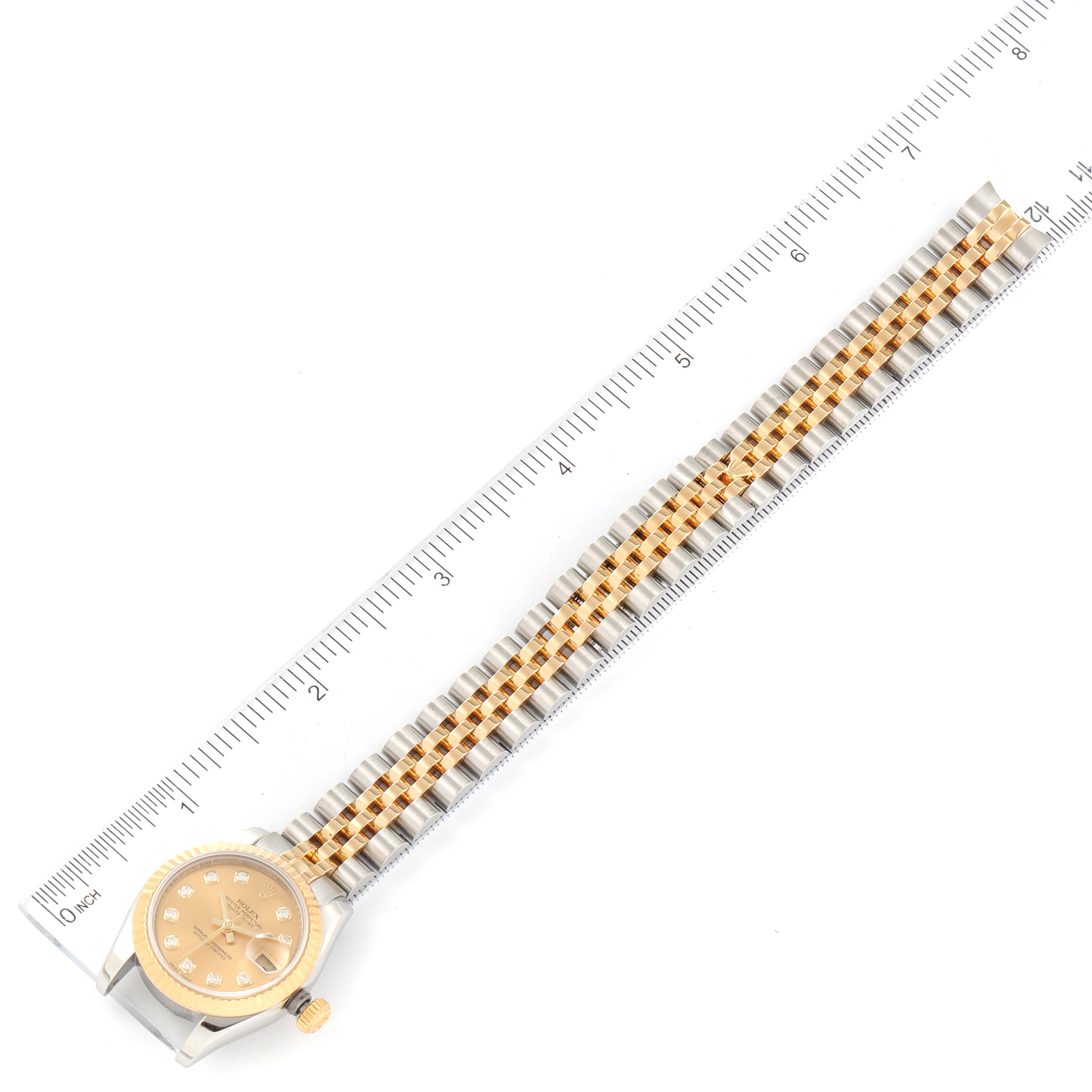 This image shows a Rolex Datejust 179173 Women
s Steel and Gold (two tone) Champagne Dial 179173 Women
s Steel and Gold (two tone) Champagne Dial watch laid flat with the face, case, and full bracelet, alongside a ruler.