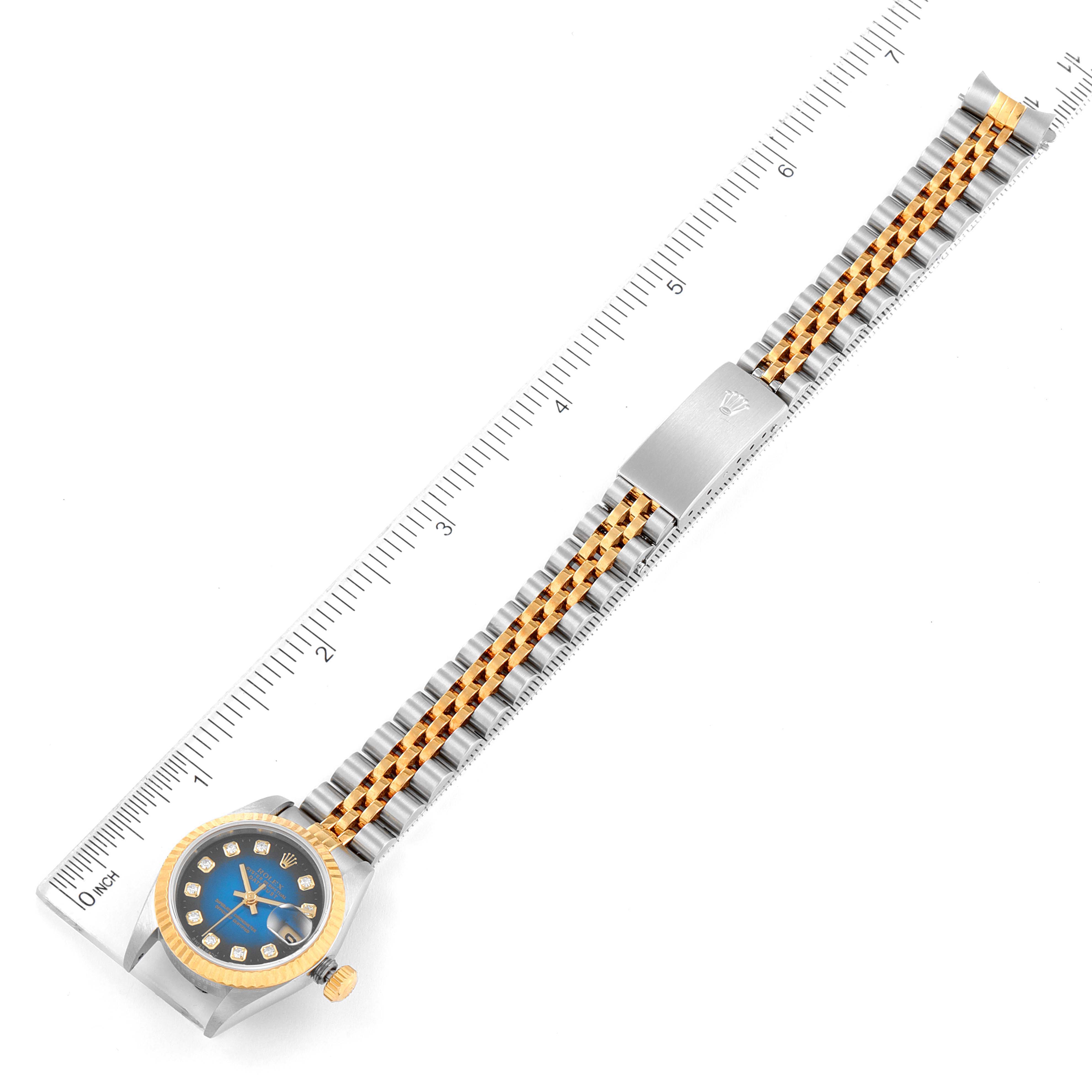 The image shows an overhead view of a Rolex Datejust 69173 Women's Steel and Gold (two tone) Blue Dial 69173 Women's Steel and Gold (two tone) Blue Dial watch with a blue dial and a two-tone bracelet beside a ruler.