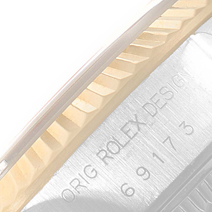 The image shows a close-up of the fluted bezel and part of the engraved case of a Rolex Datejust 69173 Women's Steel and Gold (two tone) Blue Dial 69173 Women's Steel and Gold (two tone) Blue Dial watch.