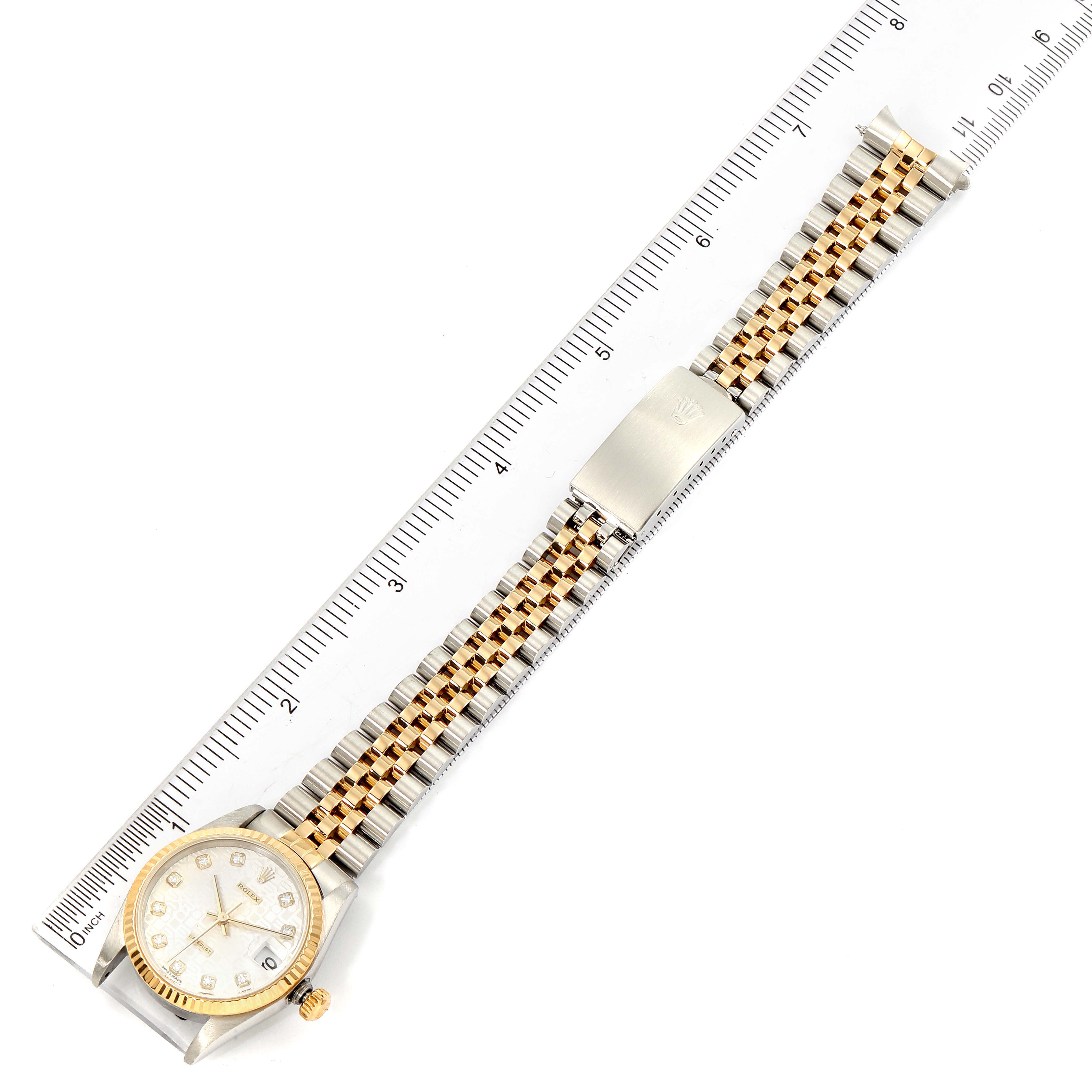 This image shows a top-down view of a Rolex Mid-Size 78273 Women
s Steel and Gold (two tone) Silver Dial 78273 Women
s Steel and Gold (two tone) Silver Dial watch with a two-tone metal bracelet and a ruler for scale.