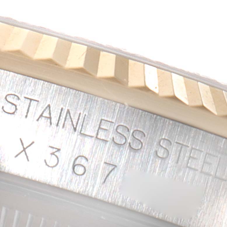 The image shows a close-up of the Rolex Datejust 16233 Men's Steel and Gold (two tone) Champagne Dial 16233 Men's Steel and Gold (two tone) Champagne Dial's bezel and fluted edge with part of the serial number engraved.