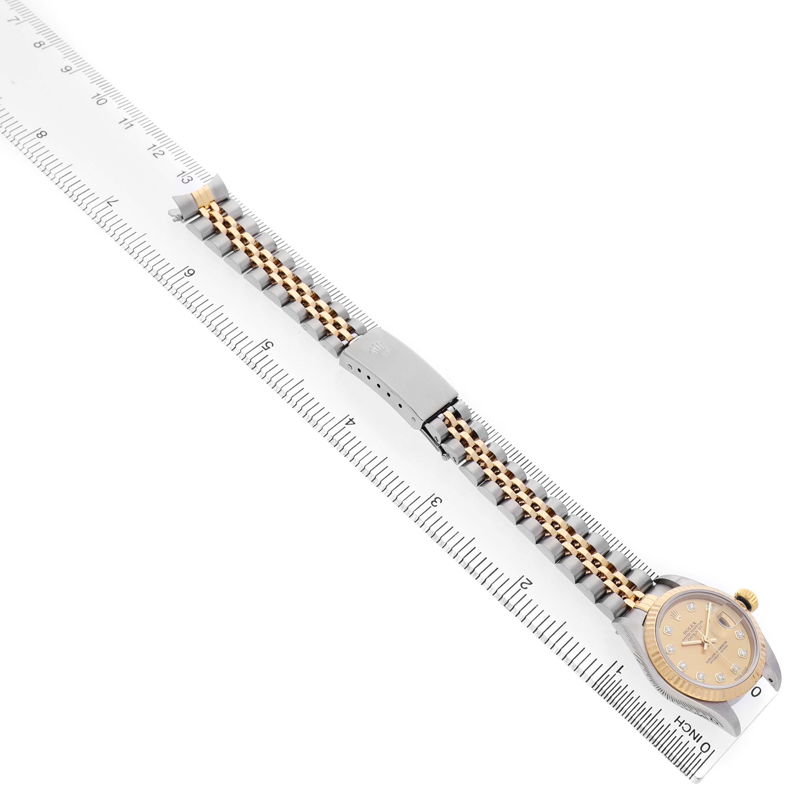 The image shows a Rolex Datejust 79173 Women's Steel and Gold (two tone) Champagne Dial watch placed alongside a ruler, highlighting its two-tone bracelet and face from a top angle.