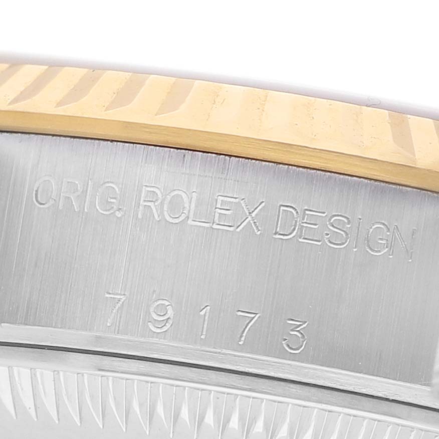The image shows a close-up of the case edge and bezel of a Rolex Datejust 79173 Women's Steel and Gold (two tone) White Dial, focusing on the engraved design and model number.
