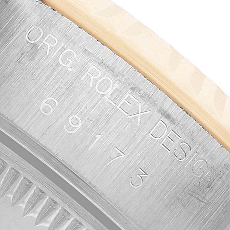 The image shows a close-up of the side of a Rolex Datejust 69173 Women's Steel and Gold (two tone) Yellow Dial watch, highlighting the engraved serial number and design inscription.