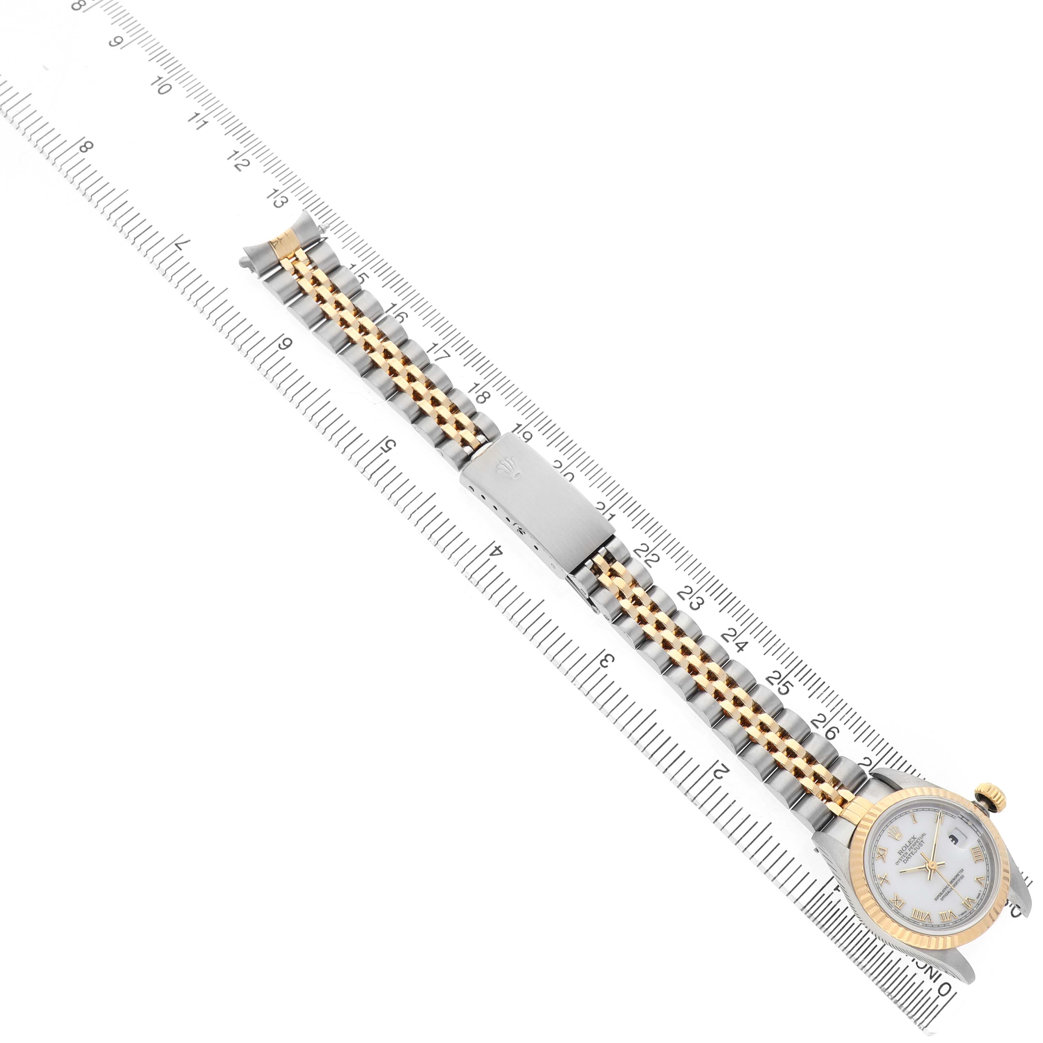 The Rolex Datejust 69173 Women's Steel and Gold (two tone) White Dial watch is shown at a diagonal angle, highlighting the bracelet and clasp alongside a ruler.