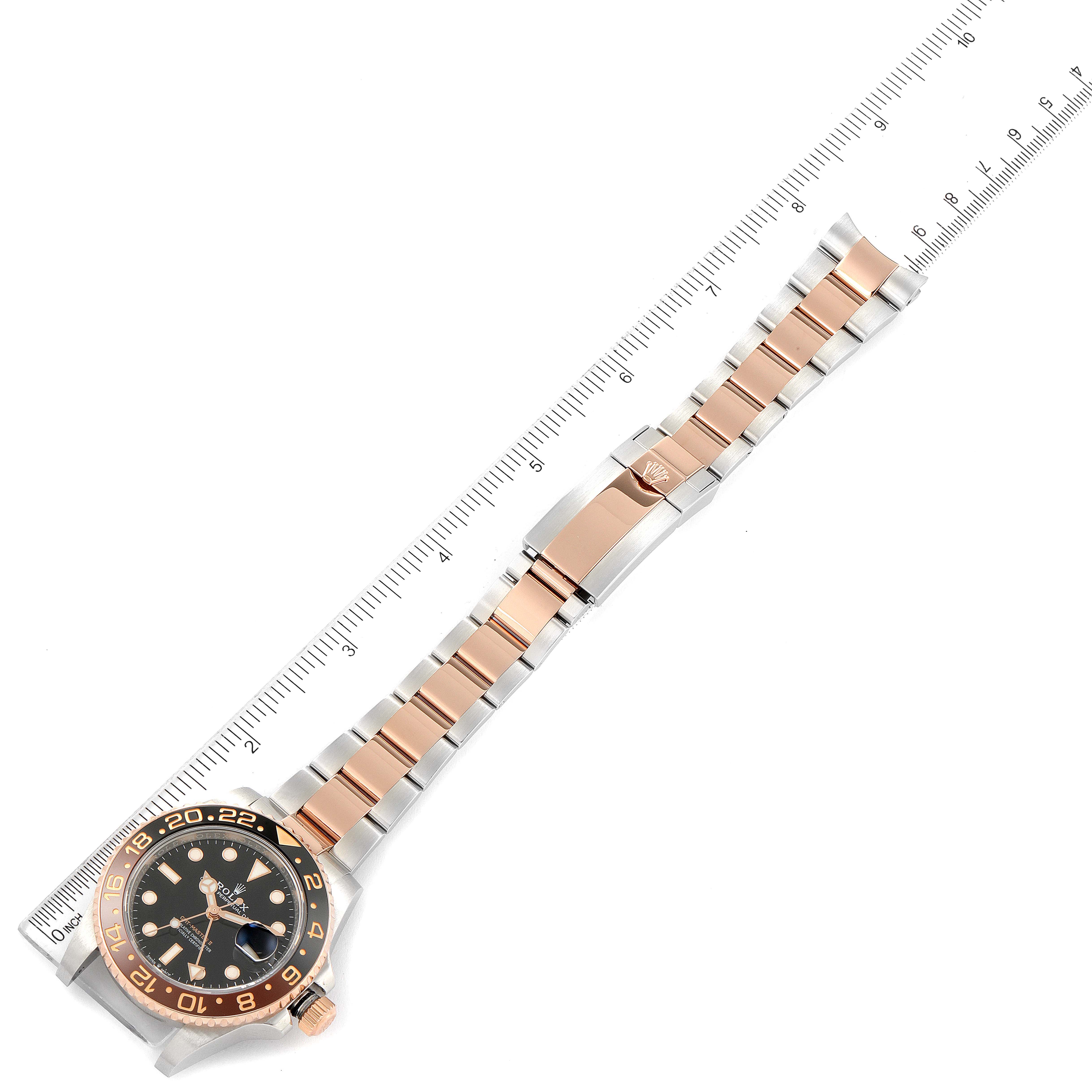 This image shows the top view of a Rolex GMT-Master 126711CHNR Men's Steel and Gold (two tone) Black Dial 126711CHNR Men's Steel and Gold (two tone) Black Dial watch, including the face, bezel, dial, case, and bracelet alongside a ruler.