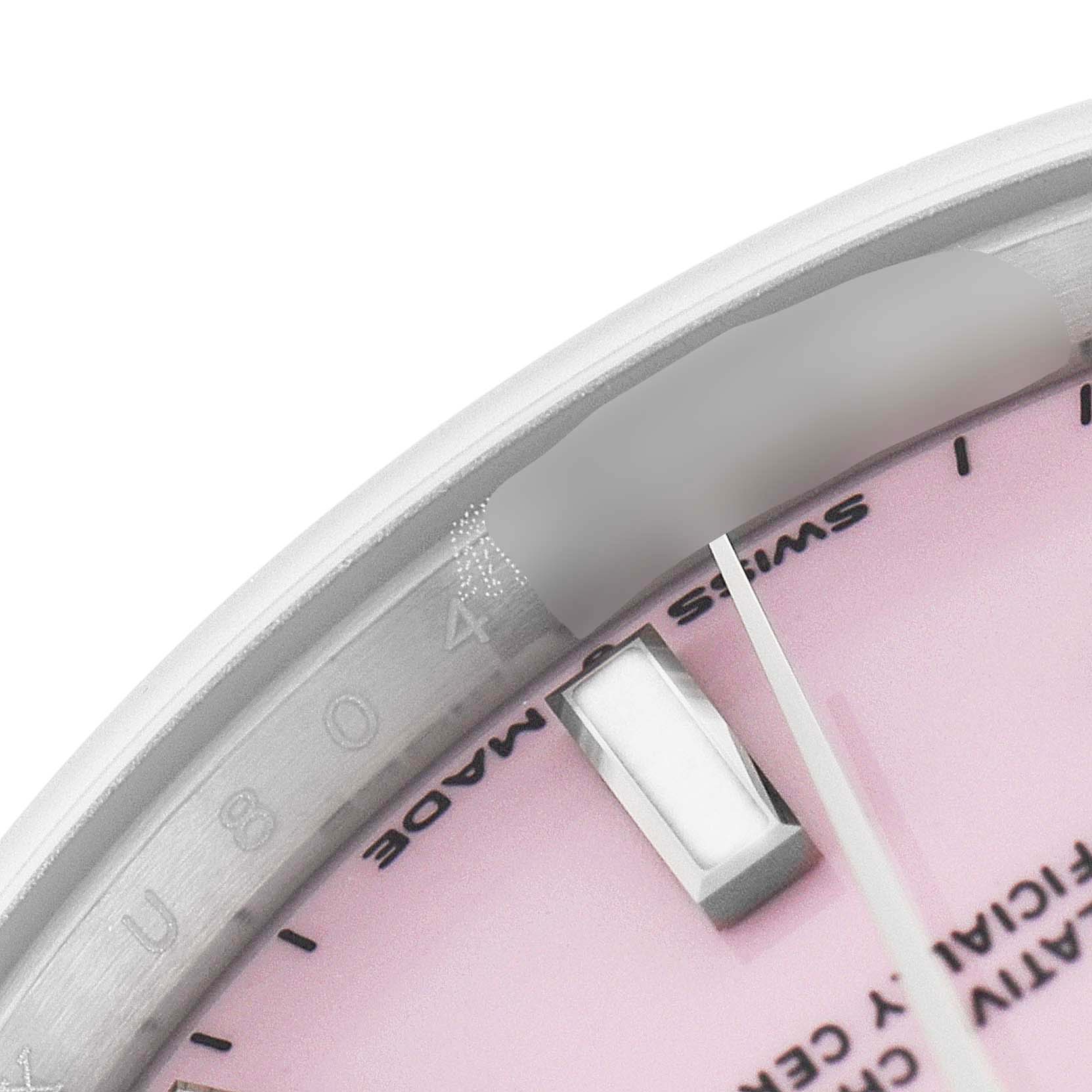 This close-up image shows a portion of the dial and bezel of a pink Mid-Size Rolex watch, highlighting part of the hour markers and text.