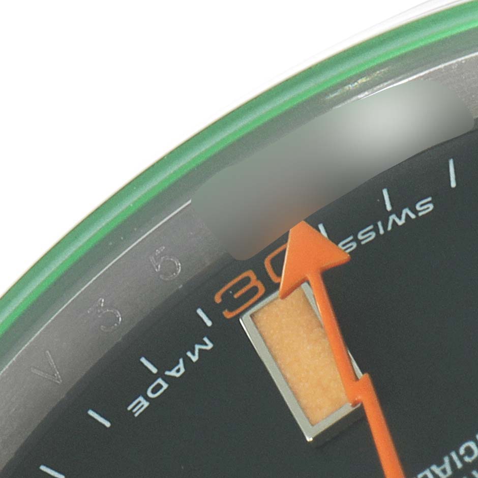 The image shows a close-up of the dial and green-tinted edge of the Rolex Milgauss 116400V Men
s Stainless Steel Black Dial 116400V Men
s Stainless Steel Black Dial watch, highlighting the "Swiss Made" text and part of the orange seconds hand.
