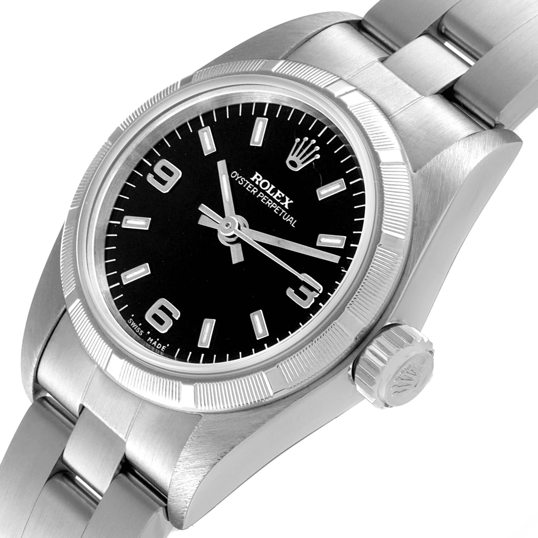 The image shows a close-up angle of a Rolex Oyster Perpetual 67230 Women's Stainless Steel Black Dial 67230 Women's Stainless Steel Black Dial watch, highlighting the black dial, bezel, crown, and metal bracelet.