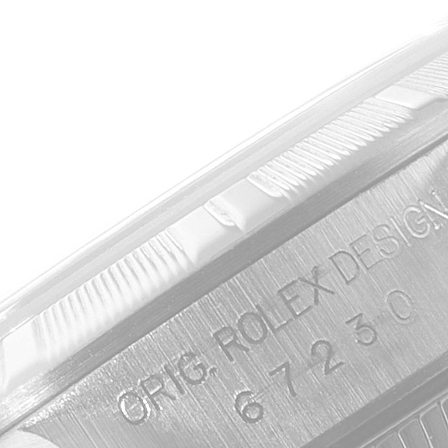 The image displays a close-up of the side casing and bezel of a Rolex Oyster Perpetual 67230 Women's Stainless Steel Black Dial 67230 Women's Stainless Steel Black Dial watch, showing the engraved model details.