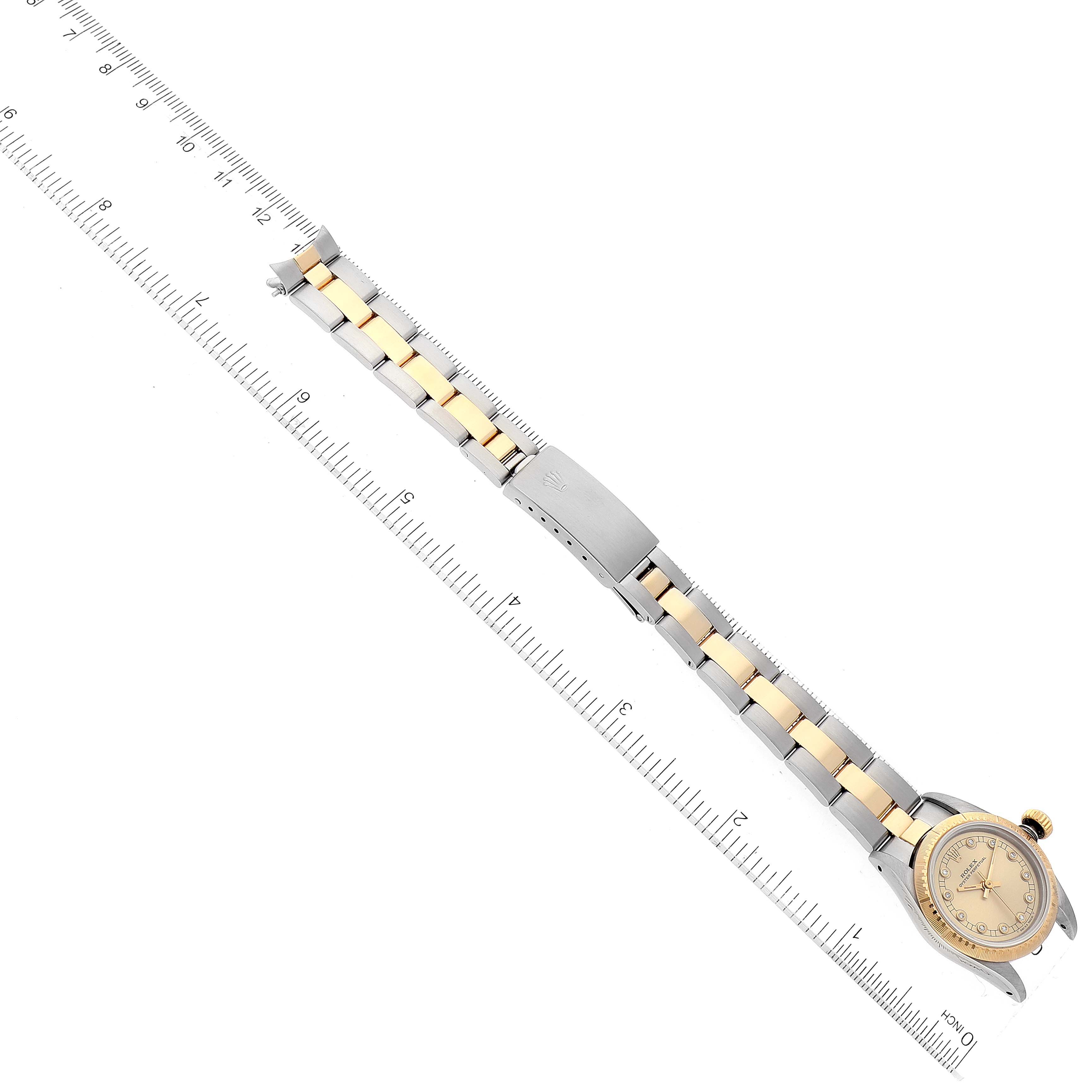 The image shows a Rolex Oyster Perpetual 67243 Women's Steel and Gold (two tone) Champagne Dial 67243 Women's Steel and Gold (two tone) Champagne Dial watch lying flat with the full strap extended next to a ruler for scale.