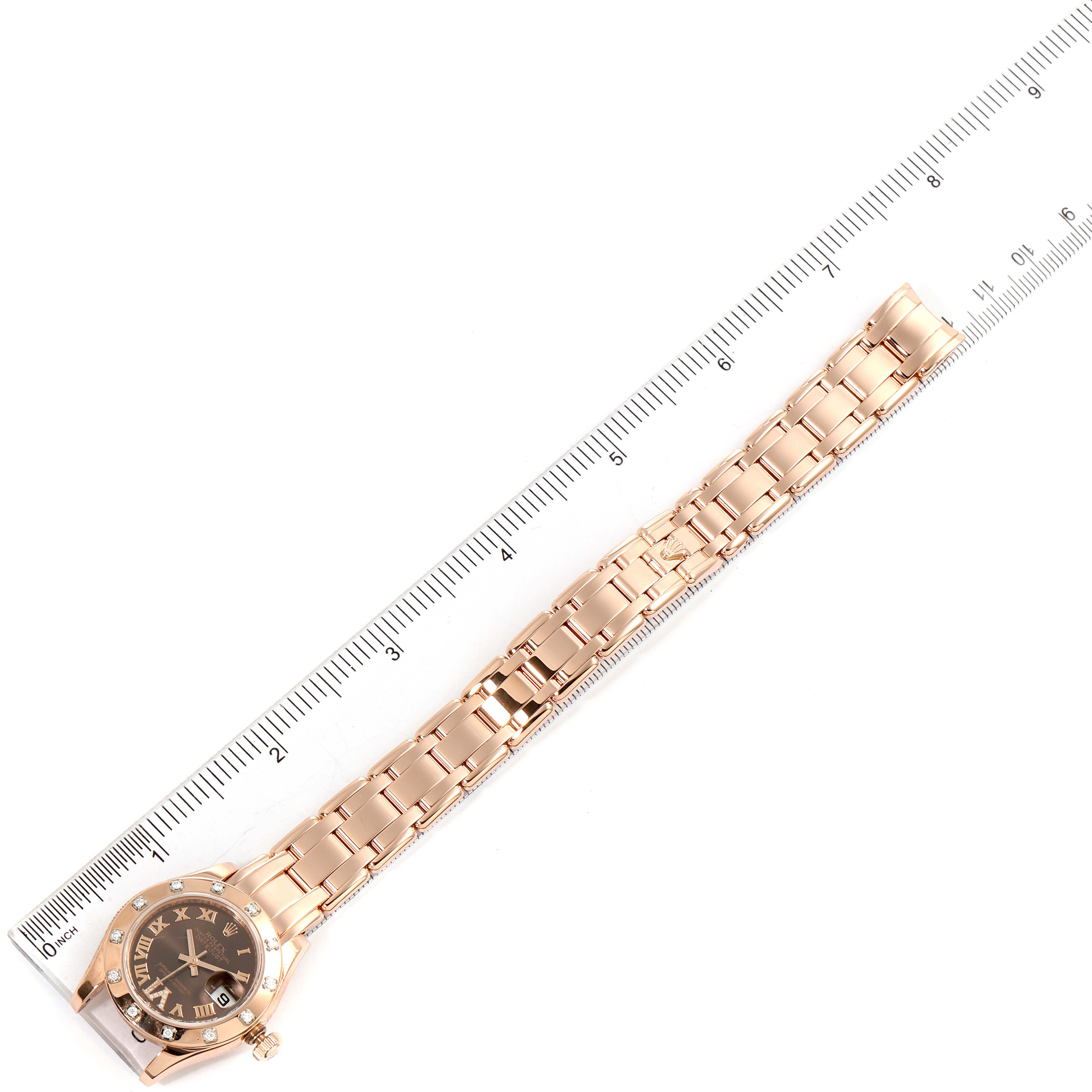 The image shows a top-down view of a Rolex Pearlmaster 80315 Women's Rose Gold Brown Dial 80315 Women's Rose Gold Brown Dial watch with its full bracelet laid out alongside a ruler.