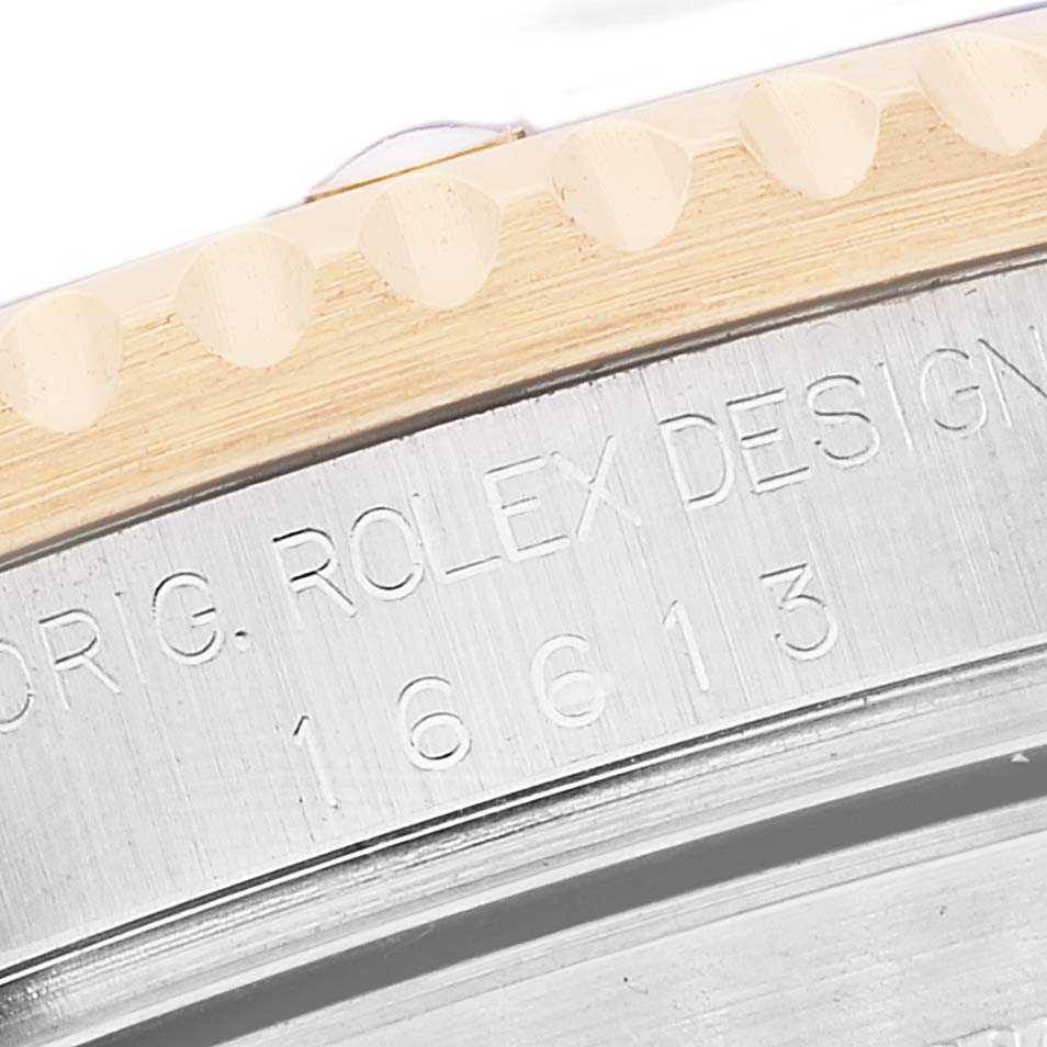This close-up angle of the Rolex Submariner 16613 Men's Steel and Gold (two tone) Grey Dial 16613 Men's Steel and Gold (two tone) Grey Dial shows part of the bezel and case with the model number and branding engraved.
