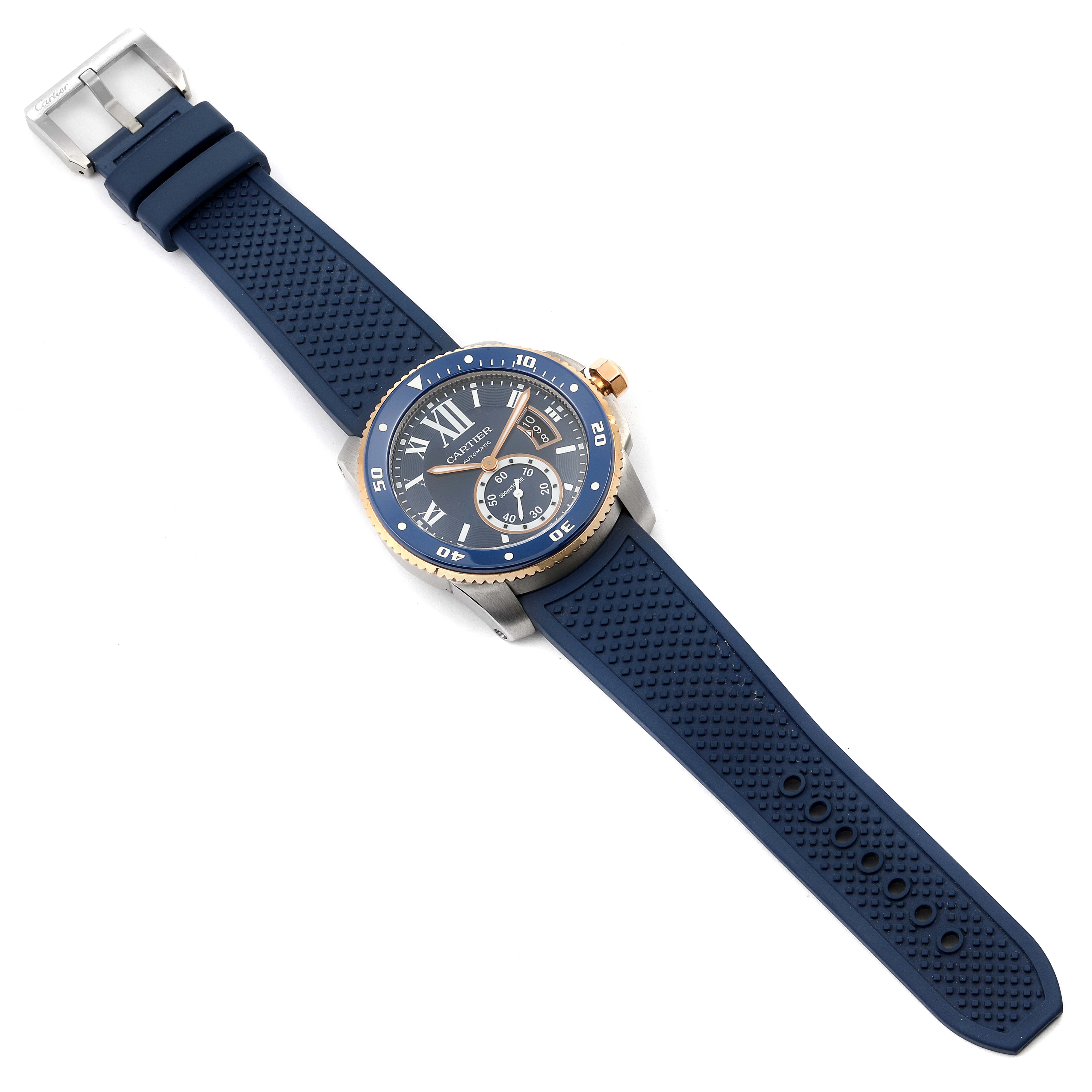 The image shows a top-down view of the Calibre de Cartier watch by Cartier, highlighting the blue strap and gold-accented bezel.