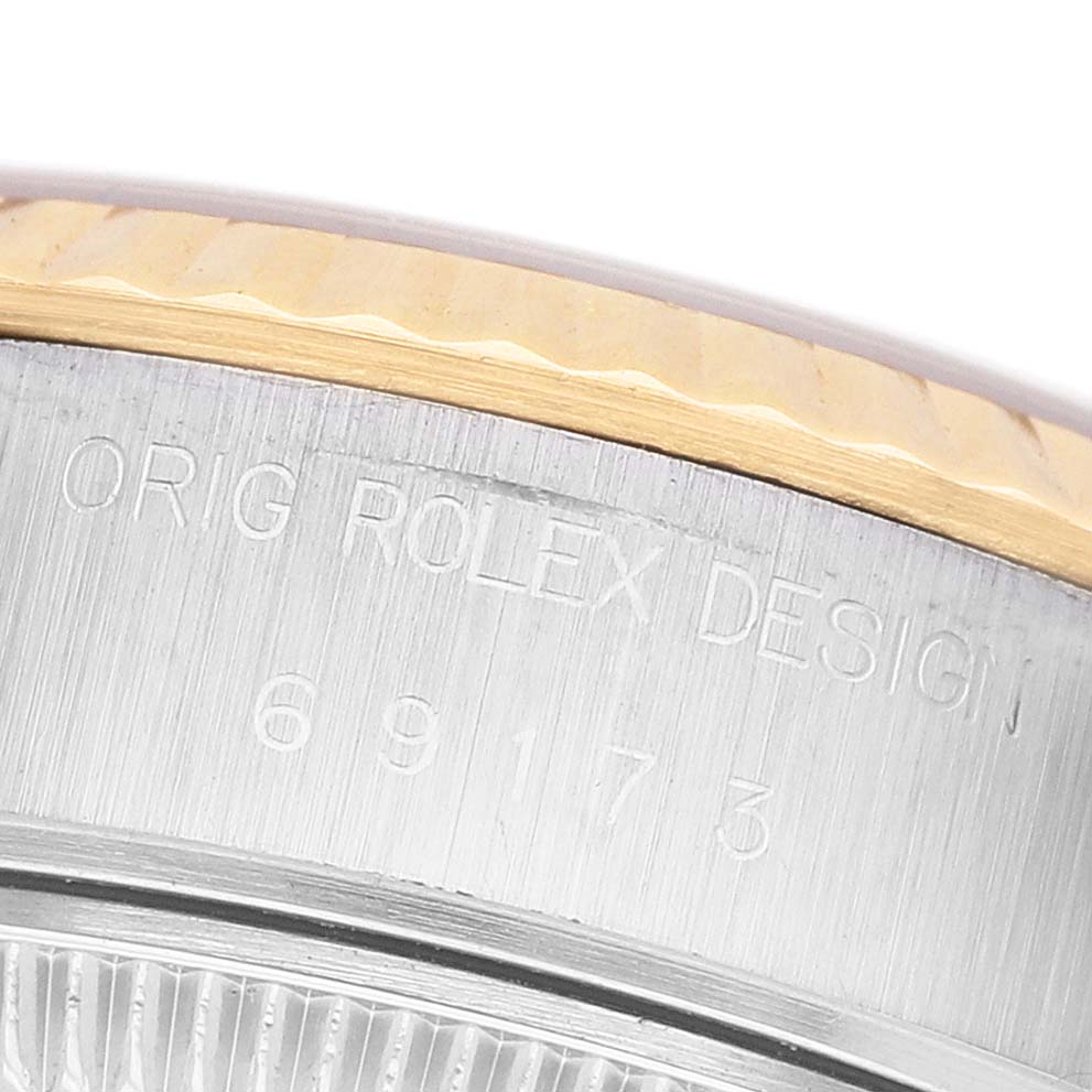 The image shows a close-up of the side of a Rolex Datejust 69173 Women's Steel and Gold (two tone) Champagne Dial watch, specifically focusing on the bezel and engraved details.