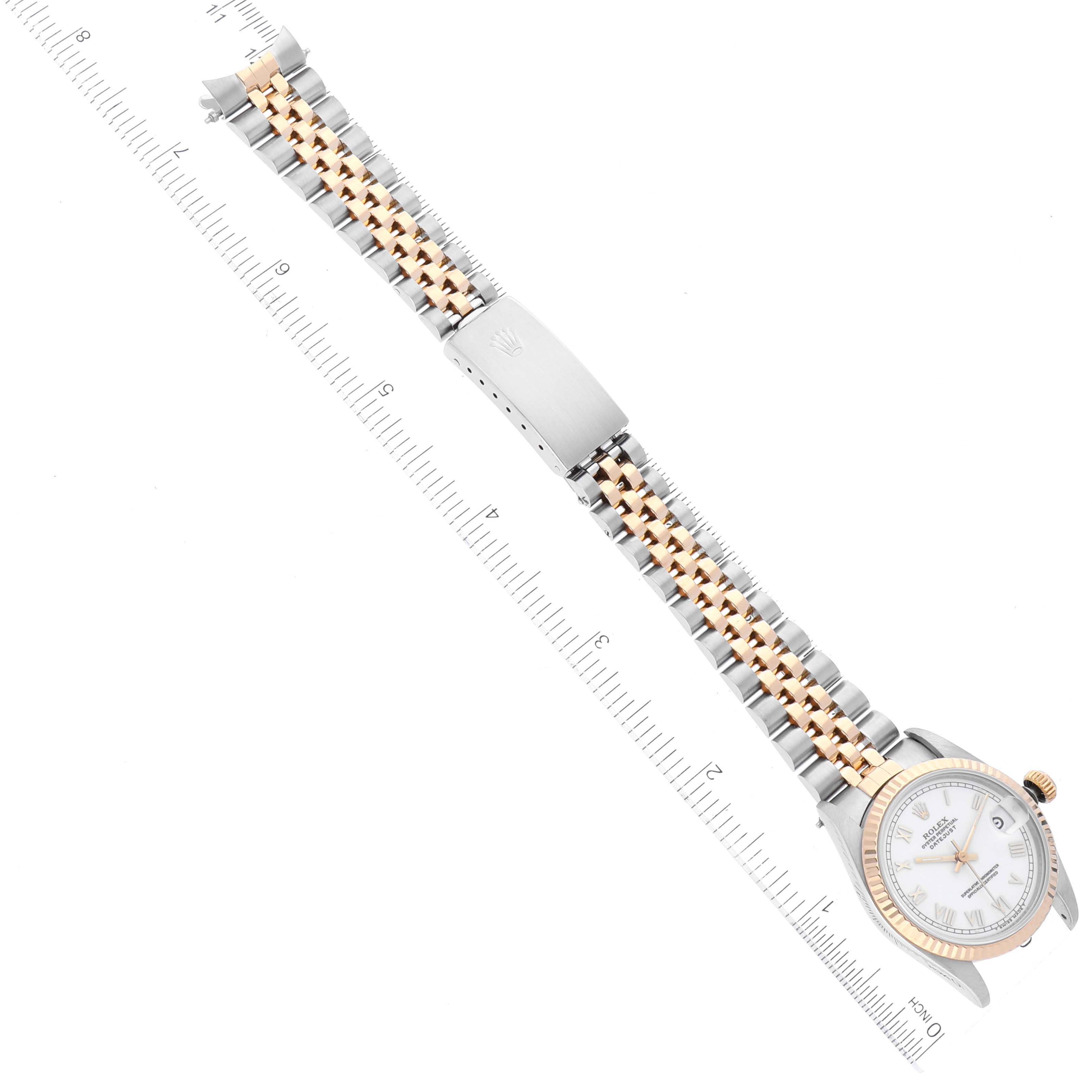 The image shows a Rolex Mid-Size 68273 Women
s Steel and Gold (two tone) White Dial 68273 Women
s Steel and Gold (two tone) White Dial model watch from a top-down angle, displaying its face, bezel, and two-tone bracelet alongside a ruler for scale.