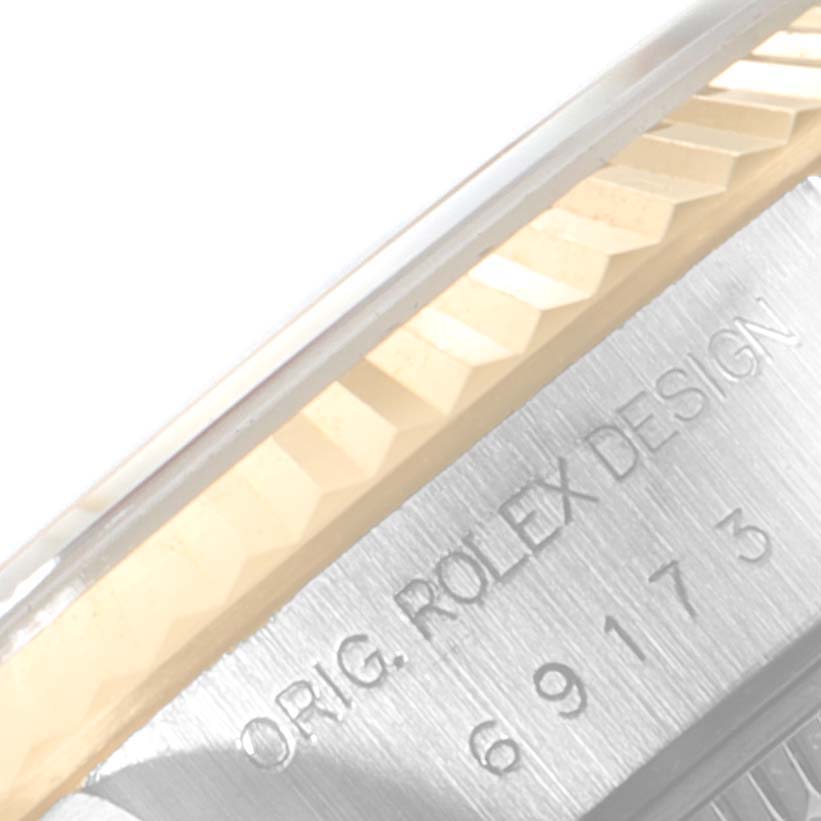 This close-up image of a Rolex Datejust 69173 Women
s Steel and Gold (two tone) Silver Dial 69173 Women
s Steel and Gold (two tone) Silver Dial watch shows part of the bezel and case with engraved writing.
