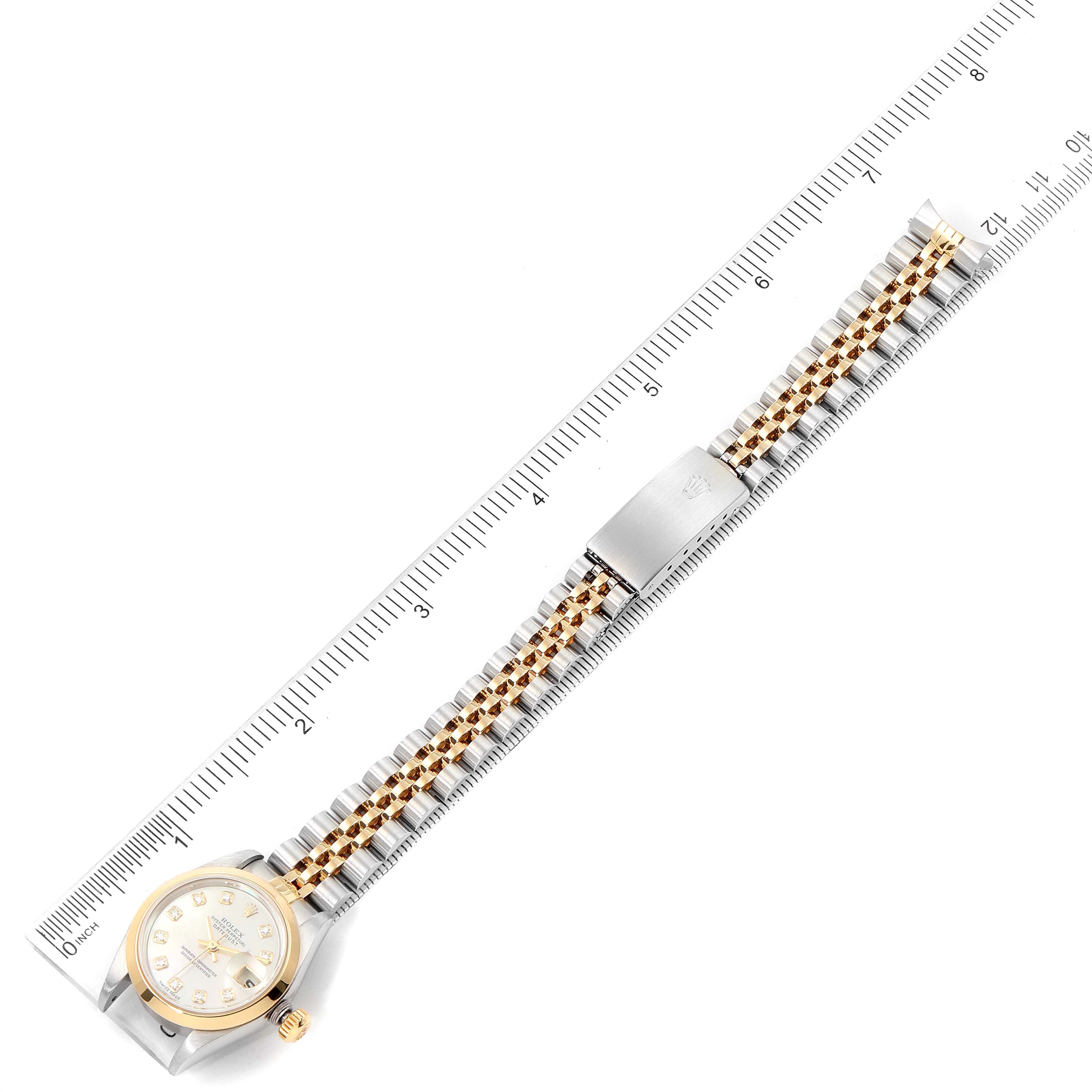 The Rolex Datejust 79163 Women's Steel and Gold (two tone) Mother of Pearl Dial 79163 Women's Steel and Gold (two tone) Mother of Pearl Dial watch is shown flat with its band extended, placed next to a ruler for scale.