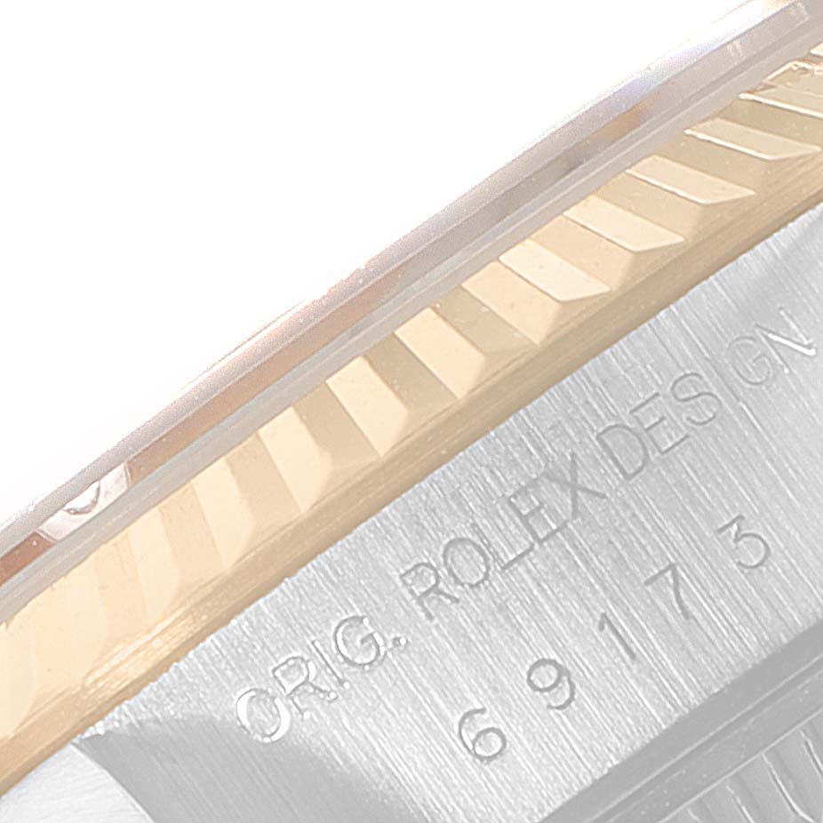This close-up image shows the side of a Rolex Datejust 69173 Women
s Steel and Gold (two tone) Champagne Dial 69173 Women
s Steel and Gold (two tone) Champagne Dial watch, highlighting the fluted bezel and case with engravings.