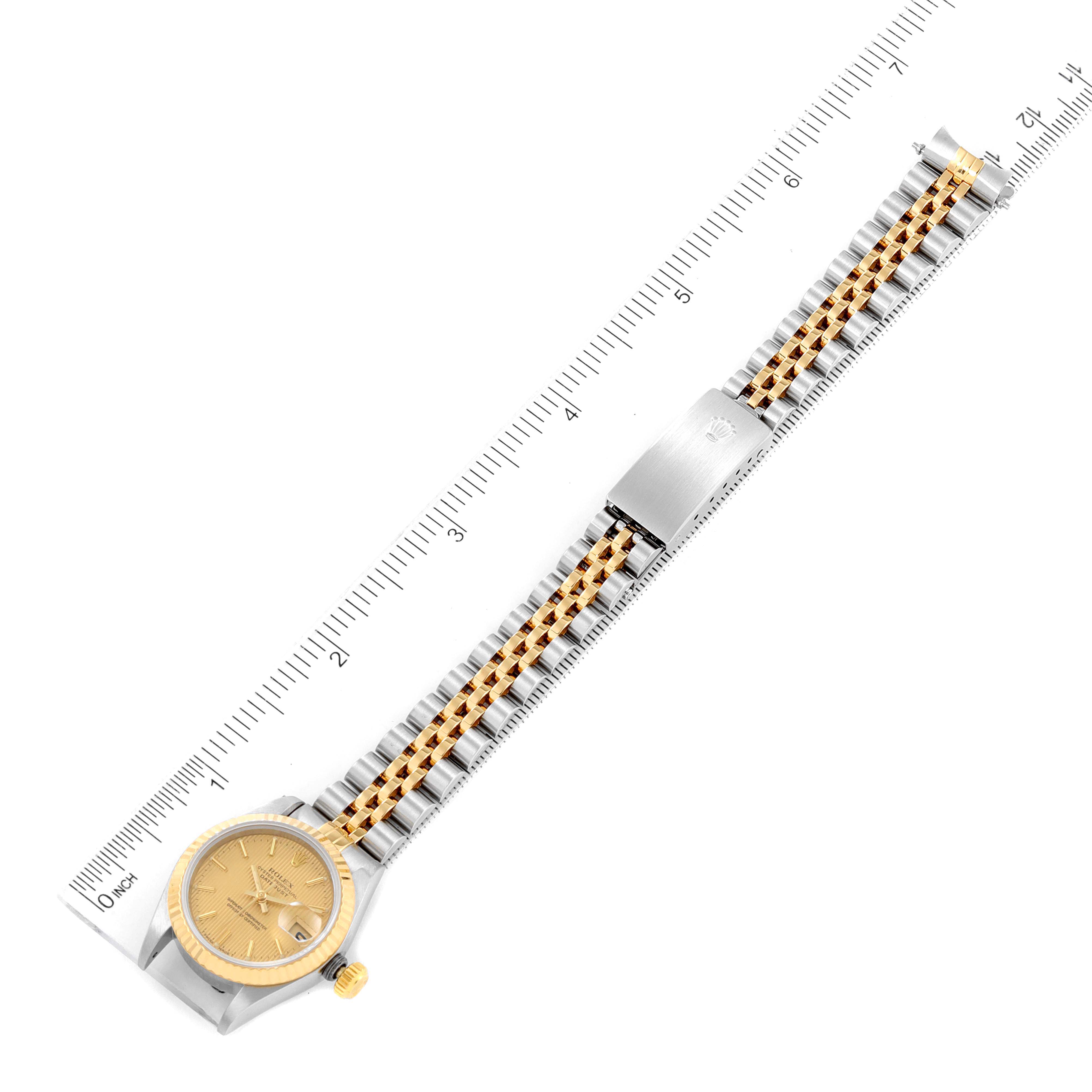 The image shows a top-down view of a Rolex Datejust 69173 Women
s Steel and Gold (two tone) Champagne Dial 69173 Women
s Steel and Gold (two tone) Champagne Dial watch with the face, bracelet, and clasp visible alongside a measurement scale.