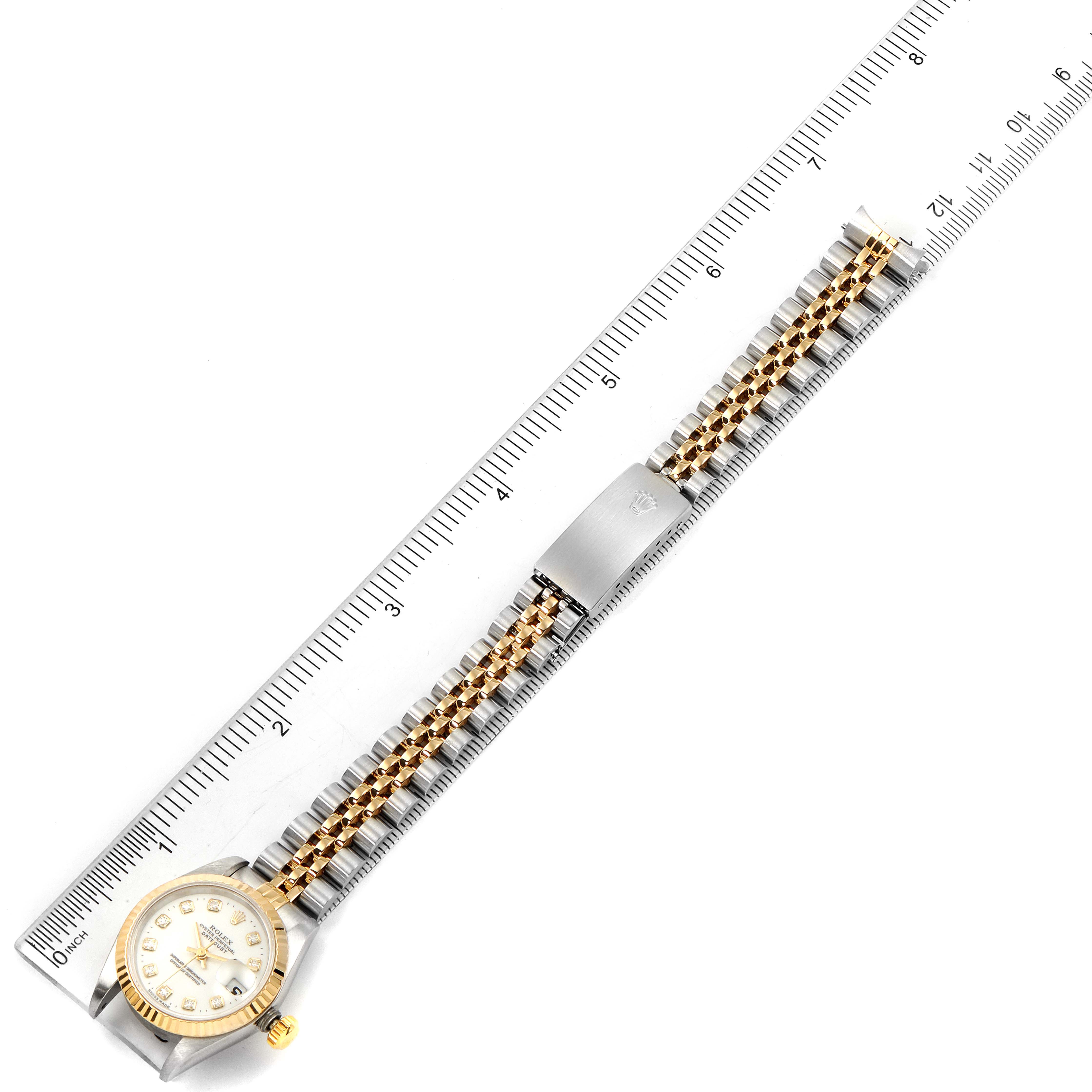 The image shows a gold and silver Rolex Datejust 69173 Women's Steel and Gold (two tone) White Dial 69173 Women's Steel and Gold (two tone) White Dial watch laid flat on a ruler, displaying the face and full length of the bracelet.