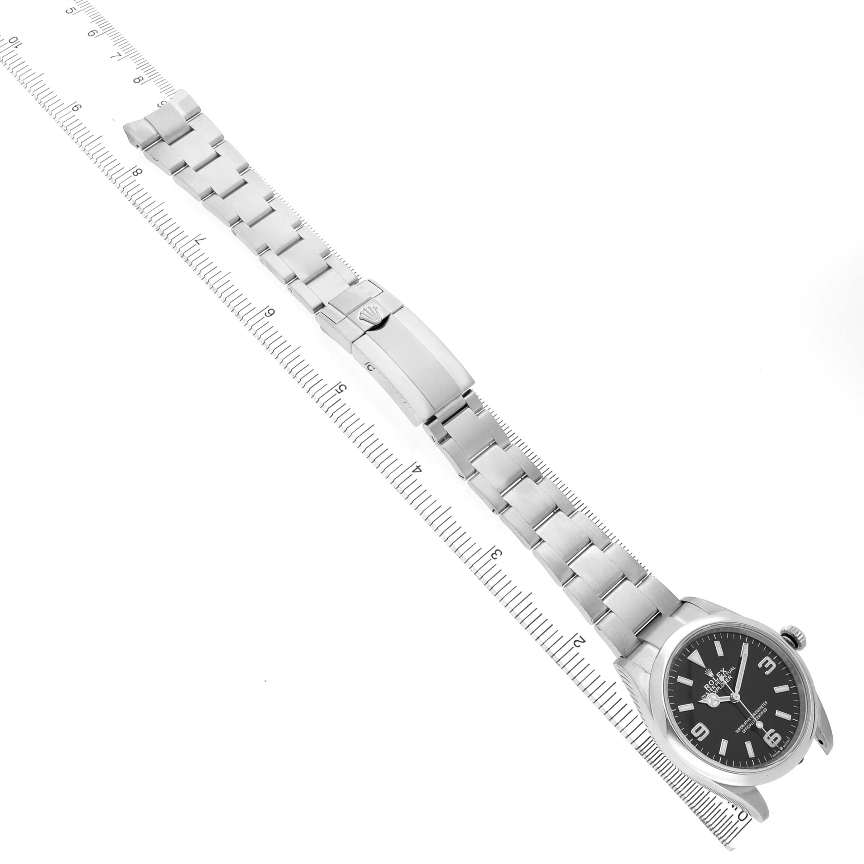 The Rolex Explorer 124270 Men's Stainless Steel Black Dial watch is shown lying flat with its bracelet extended alongside a ruler for scale.