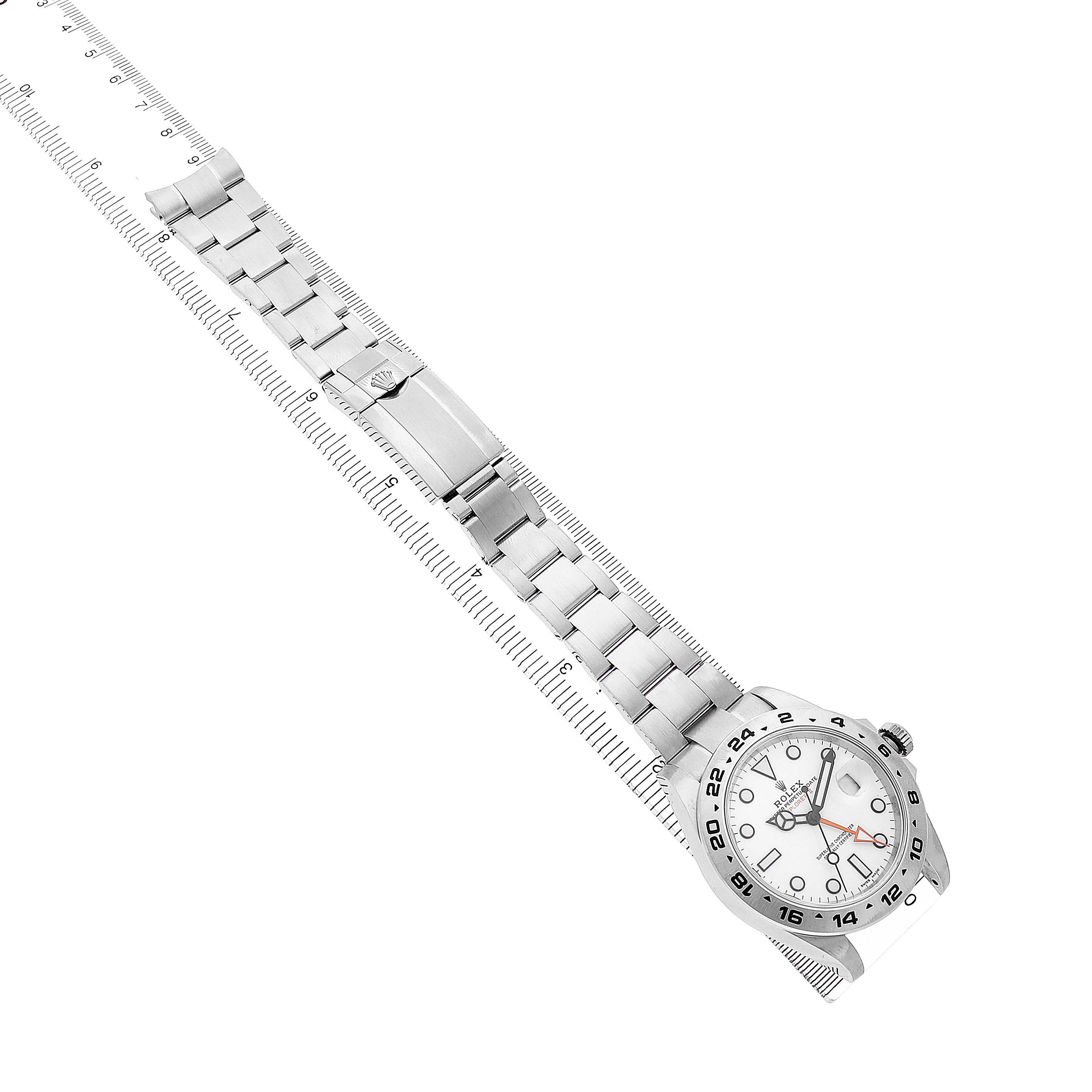 The Rolex Explorer 216570 Men's Stainless Steel White Dial watch is shown from a top-down angle, displaying the band and face next to a ruler for scale.