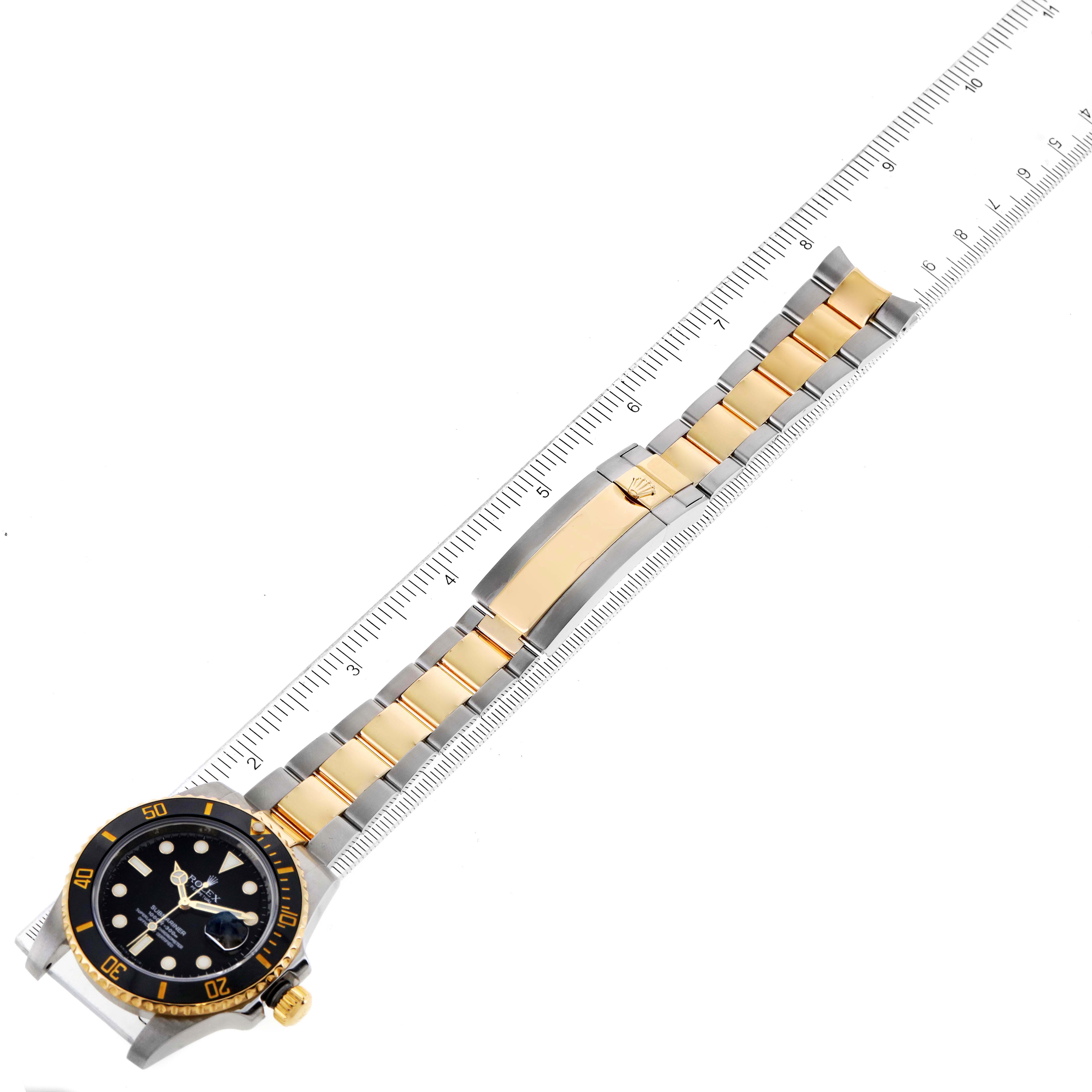 The image shows a top-down view of a Rolex Submariner 116613 Men's Steel and Gold (two tone) Black Dial 116613 Men's Steel and Gold (two tone) Black Dial watch with its bracelet aligned against a ruler for measurement.