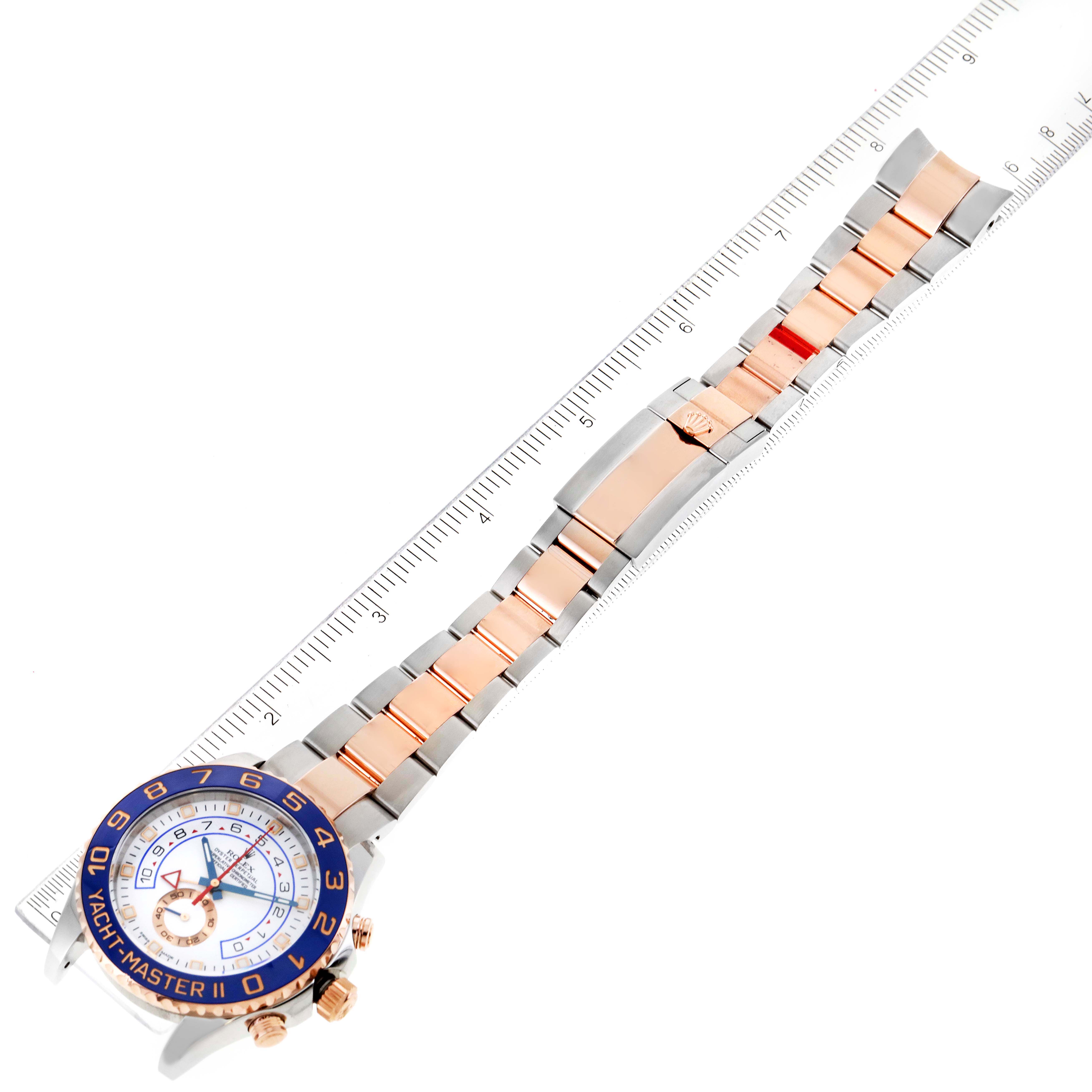 This image shows a top view of a Rolex Yacht-Master 116681 Men
s Steel and Gold (two tone) White Dial 116681 Men
s Steel and Gold (two tone) White Dial watch and its bracelet, aligned with a ruler for scale.