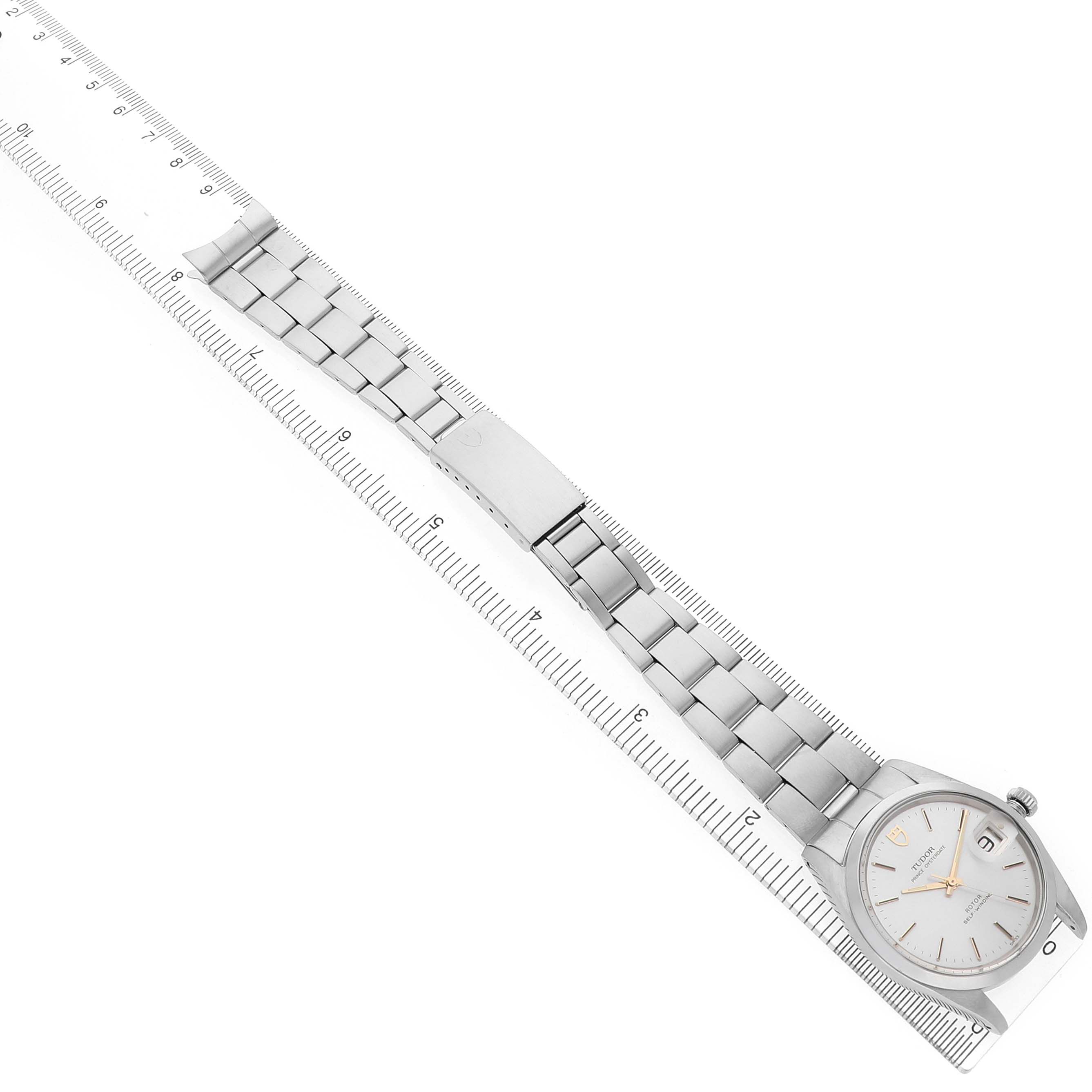 The Tudor Prince 74000 Men's Stainless Steel Silver Dial watch is displayed from a top-down angle showing the full bracelet, clasp, and face, aligned with a ruler.