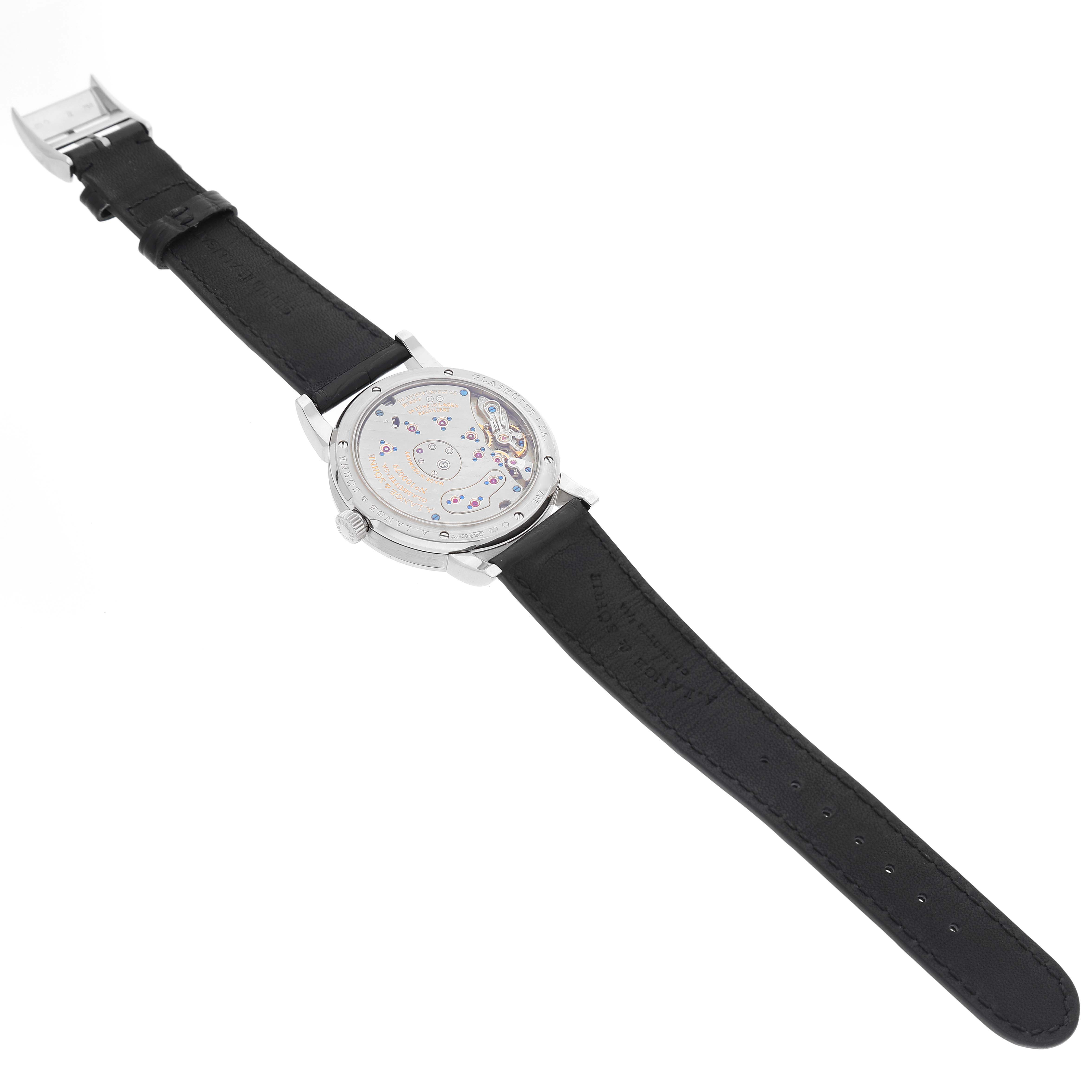 The image shows the back view of an A. Lange & Sohne Lange 1 101.039 Men's White Gold Silver Dial watch with visible mechanical movement and a black leather strap.