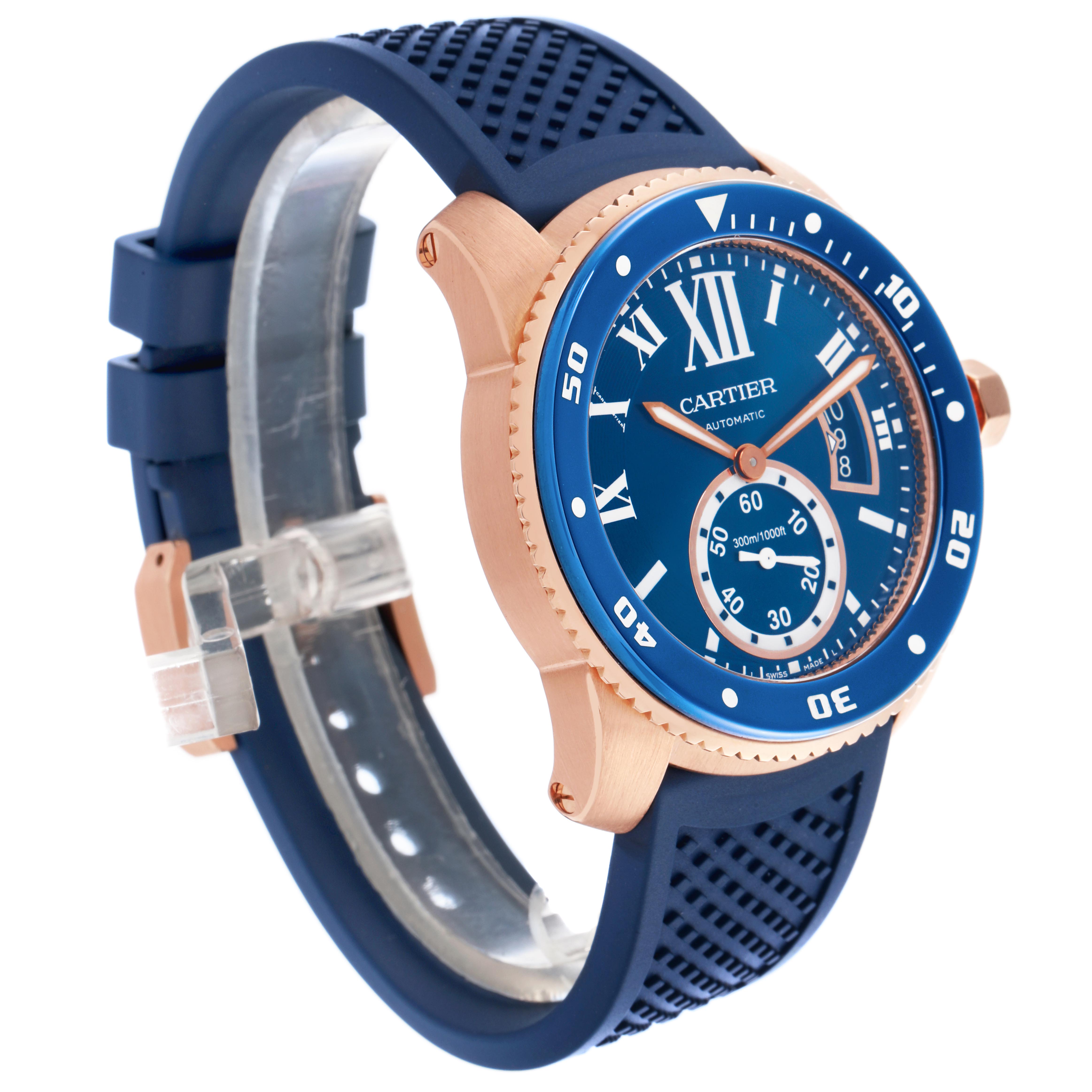 The Calibre de Cartier watch is shown at an angle highlighting the blue dial, gold case, rotating bezel, and blue rubber strap.