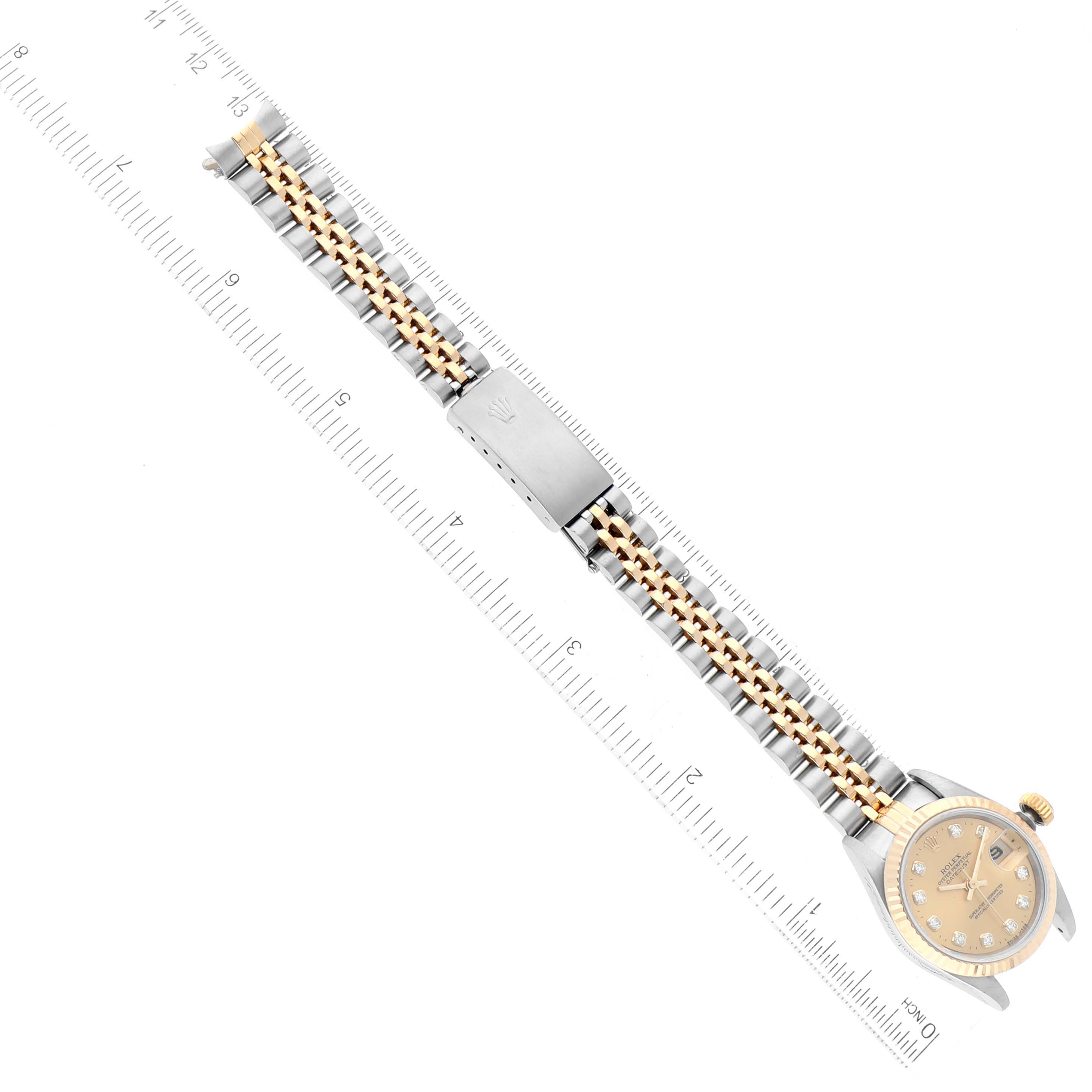 The image shows a full view of the Rolex Datejust 69173 Women's Steel and Gold (two tone) Champagne Dial 69173 Women's Steel and Gold (two tone) Champagne Dial watch, including the dial and the bracelet, laid next to a ruler.