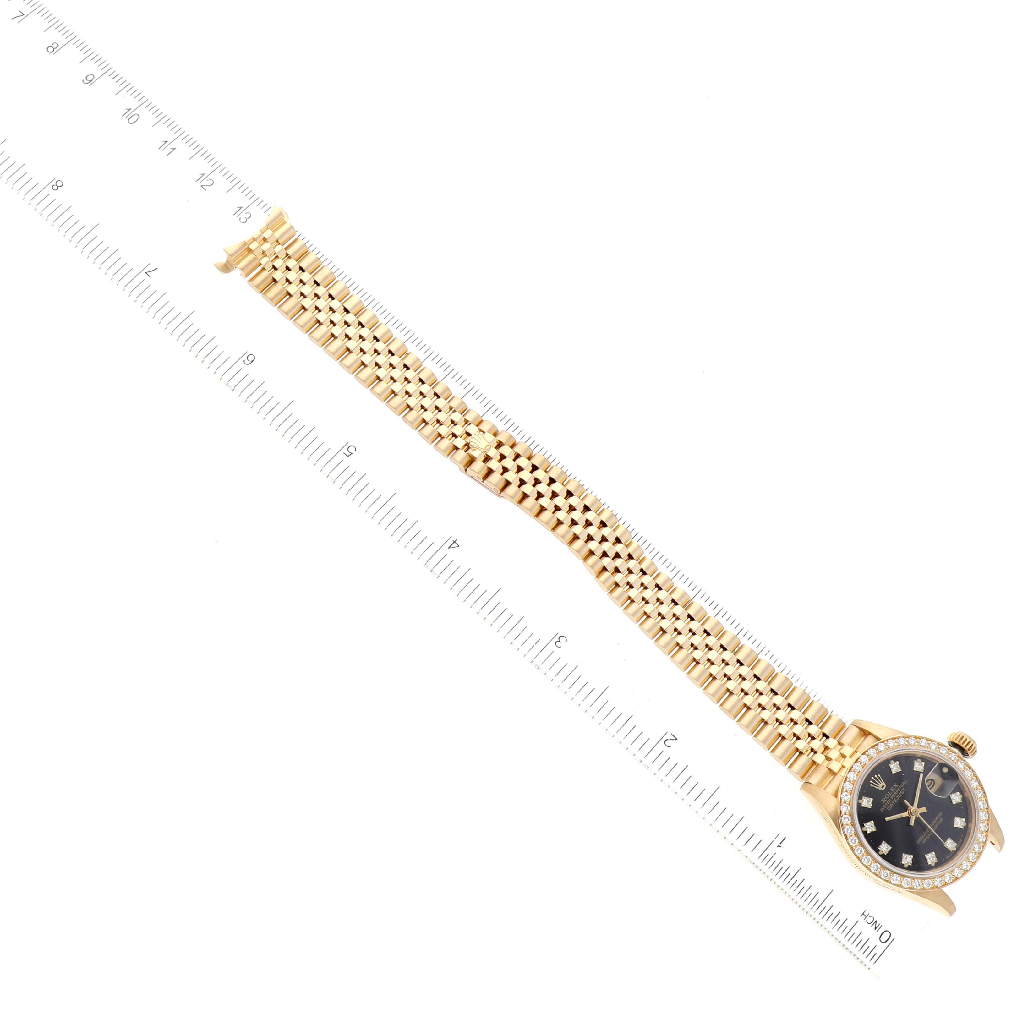 This image shows a top-down angle of the Rolex President 69138 Women's Yellow Gold Black Dial 69138 Women's Yellow Gold Black Dial watch, including the face, bezel, and full-length bracelet alongside a ruler.
