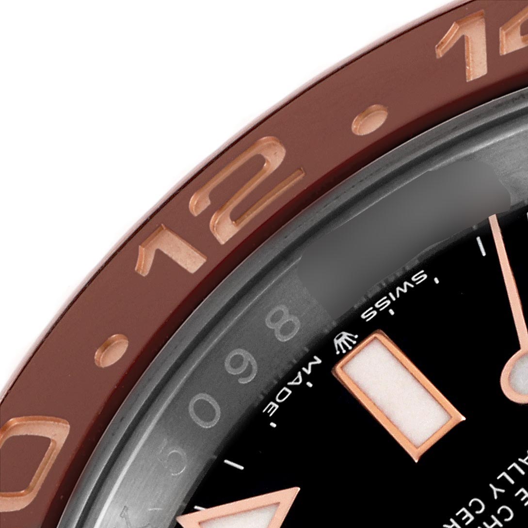 The image shows a close-up of the Rolex GMT-Master 126711CHNR Men's Steel and Gold (two tone) Black Dial 126711CHNR Men's Steel and Gold (two tone) Black Dial’s bezel and part of the dial at an angle.