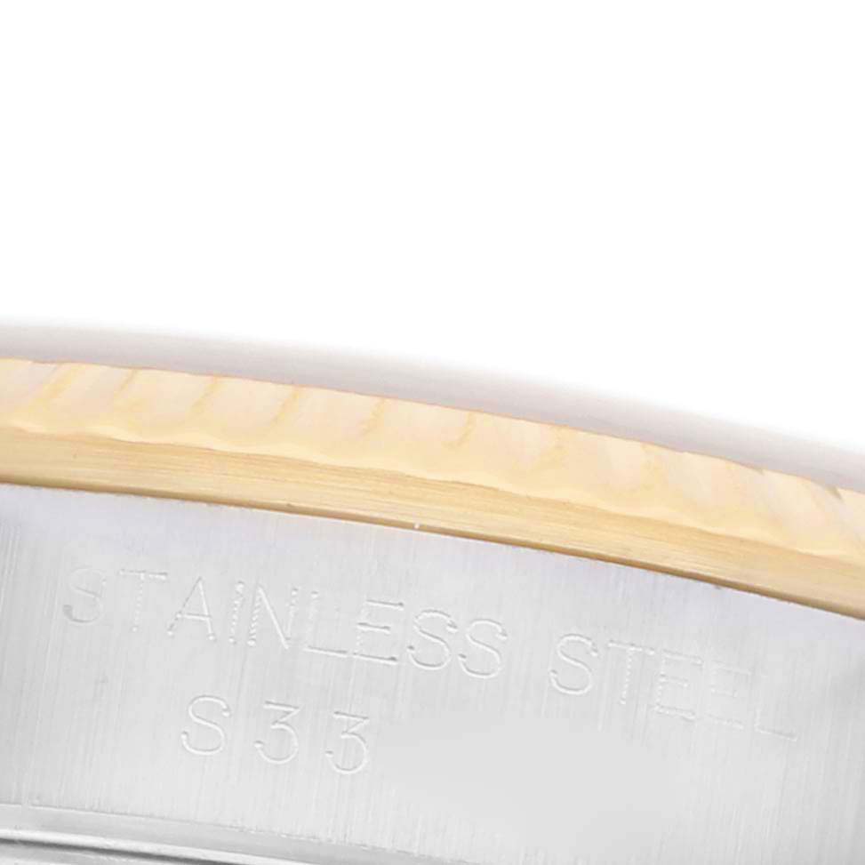The image shows a close-up of the Rolex Oyster Perpetual 67193 Women's Steel and Gold (two tone) Champagne Dial 67193 Women's Steel and Gold (two tone) Champagne Dial model's stainless steel case with engraved text.