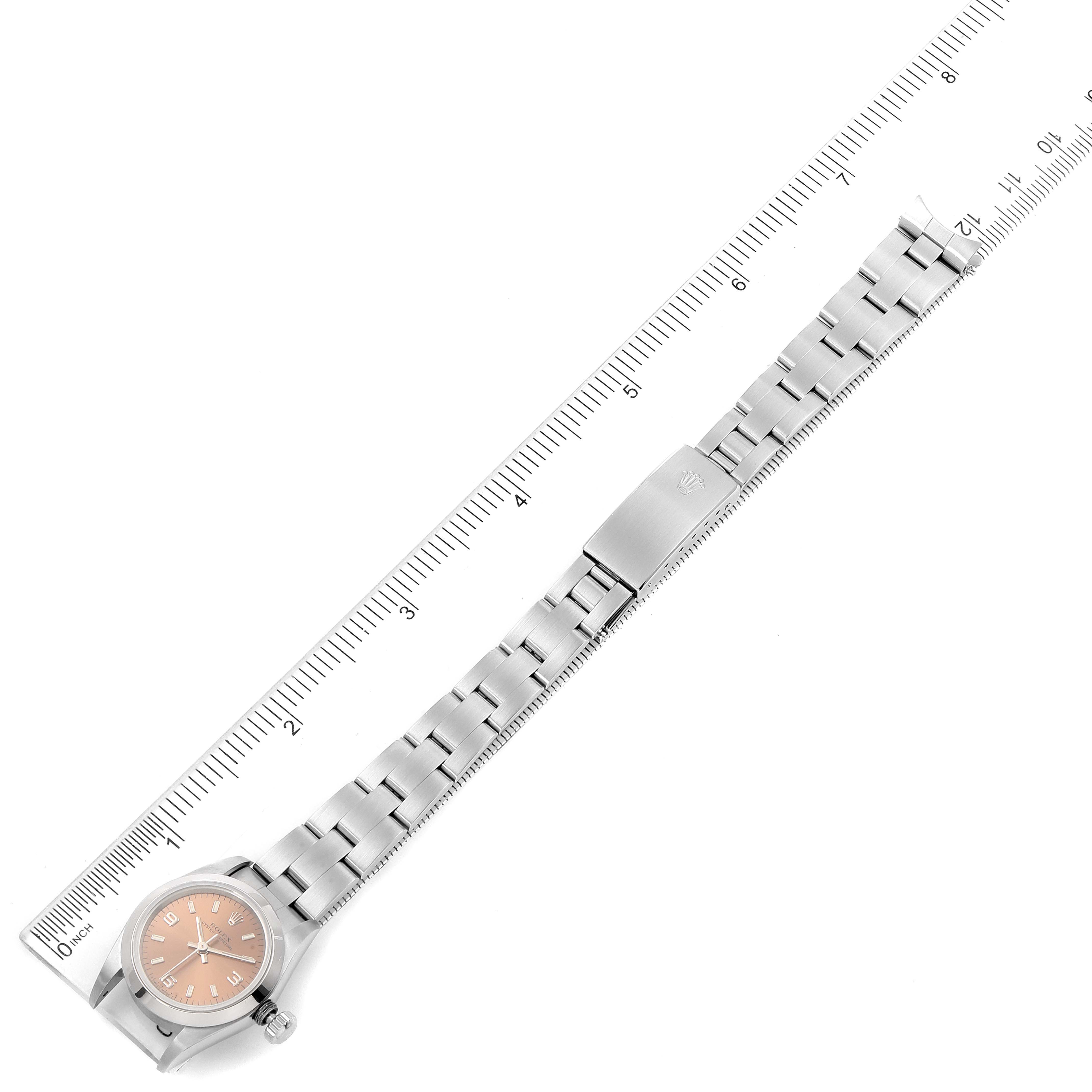 The image shows a Rolex Oyster Perpetual 67180 Women's Stainless Steel Pink Dial 67180 Women's Stainless Steel Pink Dial watch laid flat with its strap extended, next to a ruler for measurement.