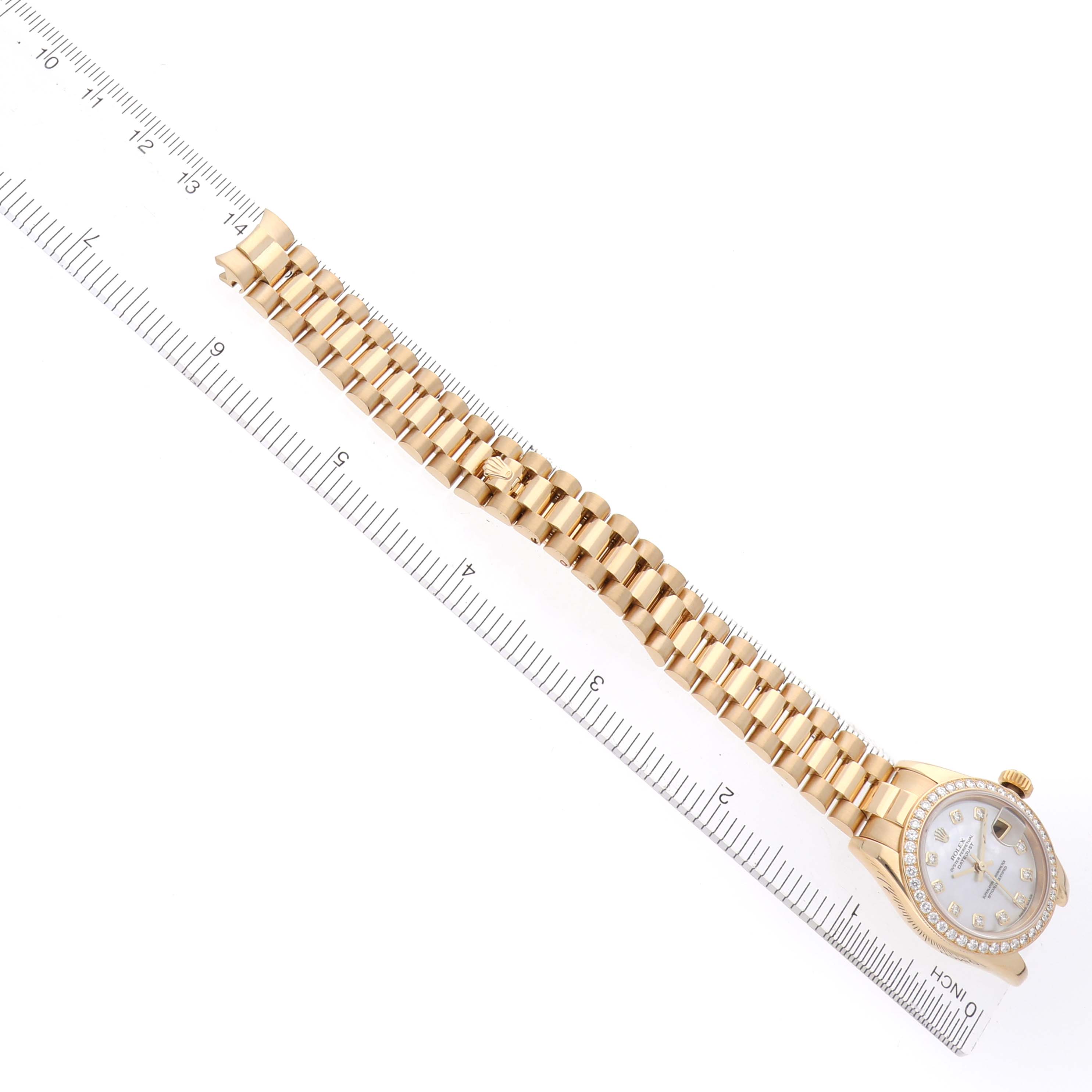 The Rolex President 179138 Women's Yellow Gold Mother of Pearl Dial 179138 Women's Yellow Gold Mother of Pearl Dial model watch is shown from a top-down angle, displaying the face and full bracelet alongside a ruler.