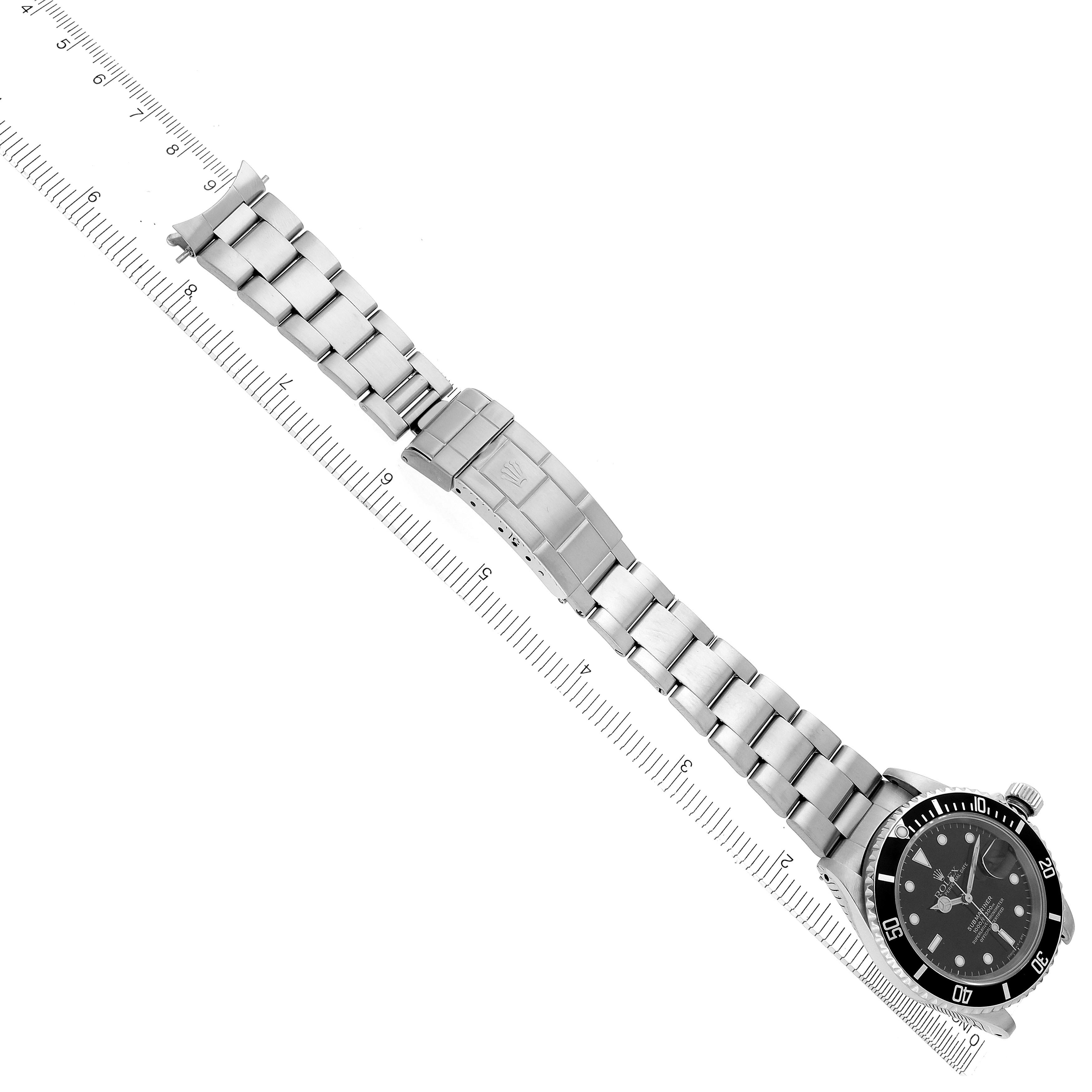 The Rolex Submariner 16610 Men's Stainless Steel Black Dial 16610 Men's Stainless Steel Black Dial watch is shown from a top-down angle, displaying its full bracelet, clasp, and face near a ruler.