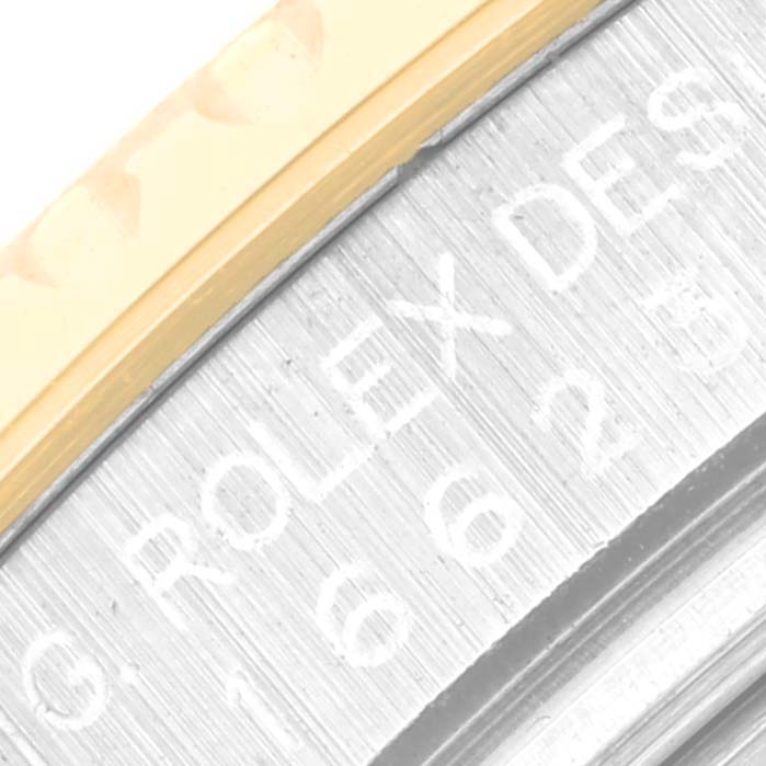 This close-up image of the Rolex Yacht-Master 16623 Men
s Steel and Gold (two tone) White Dial 16623 Men
s Steel and Gold (two tone) White Dial watch shows a portion of the bezel and the engraved edge of the case.