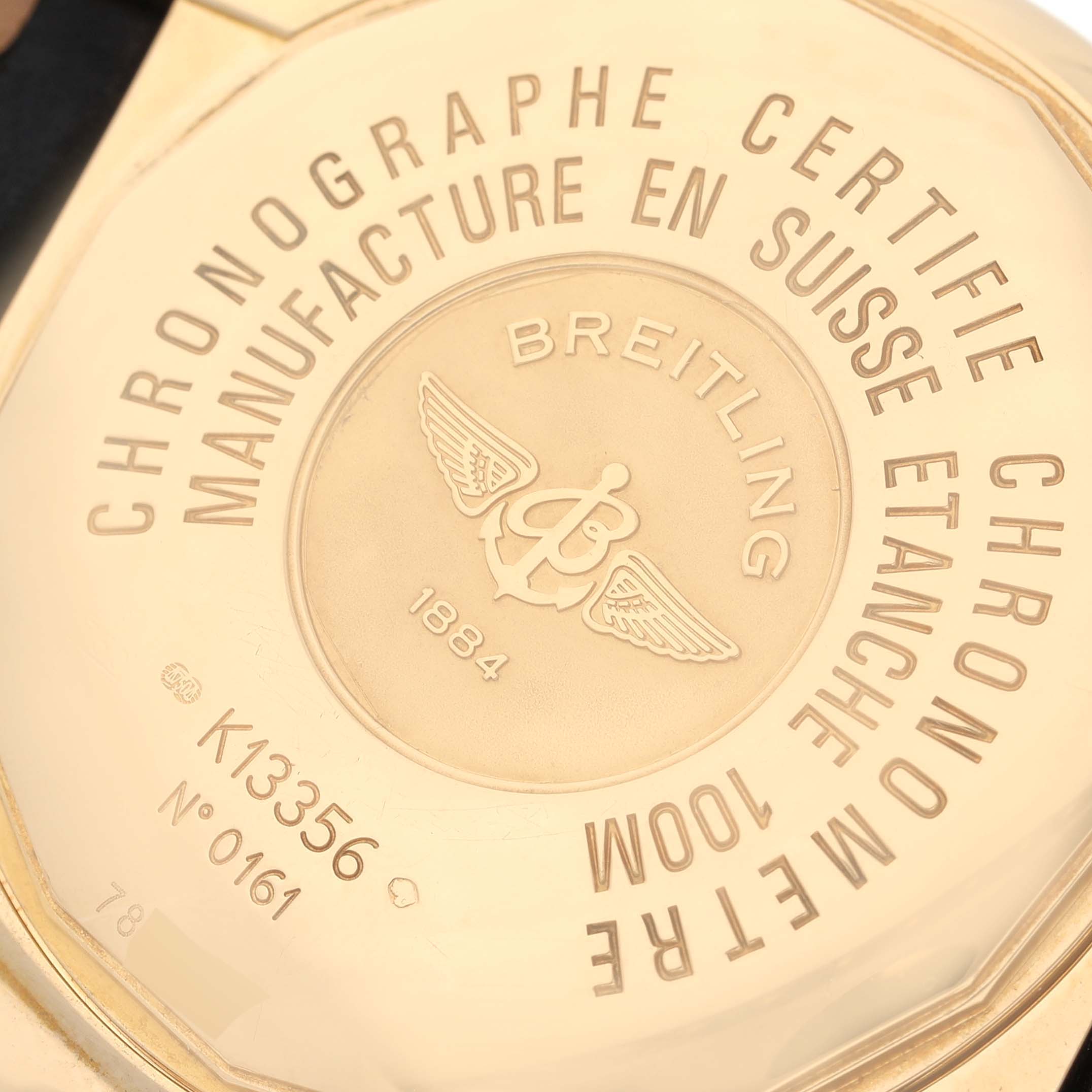 This image shows the back case of a Breitling Chronomat K13356 Men
s Yellow Gold Black Dial K13356 Men
s Yellow Gold Black Dial watch, highlighting its engravings and serial numbers.