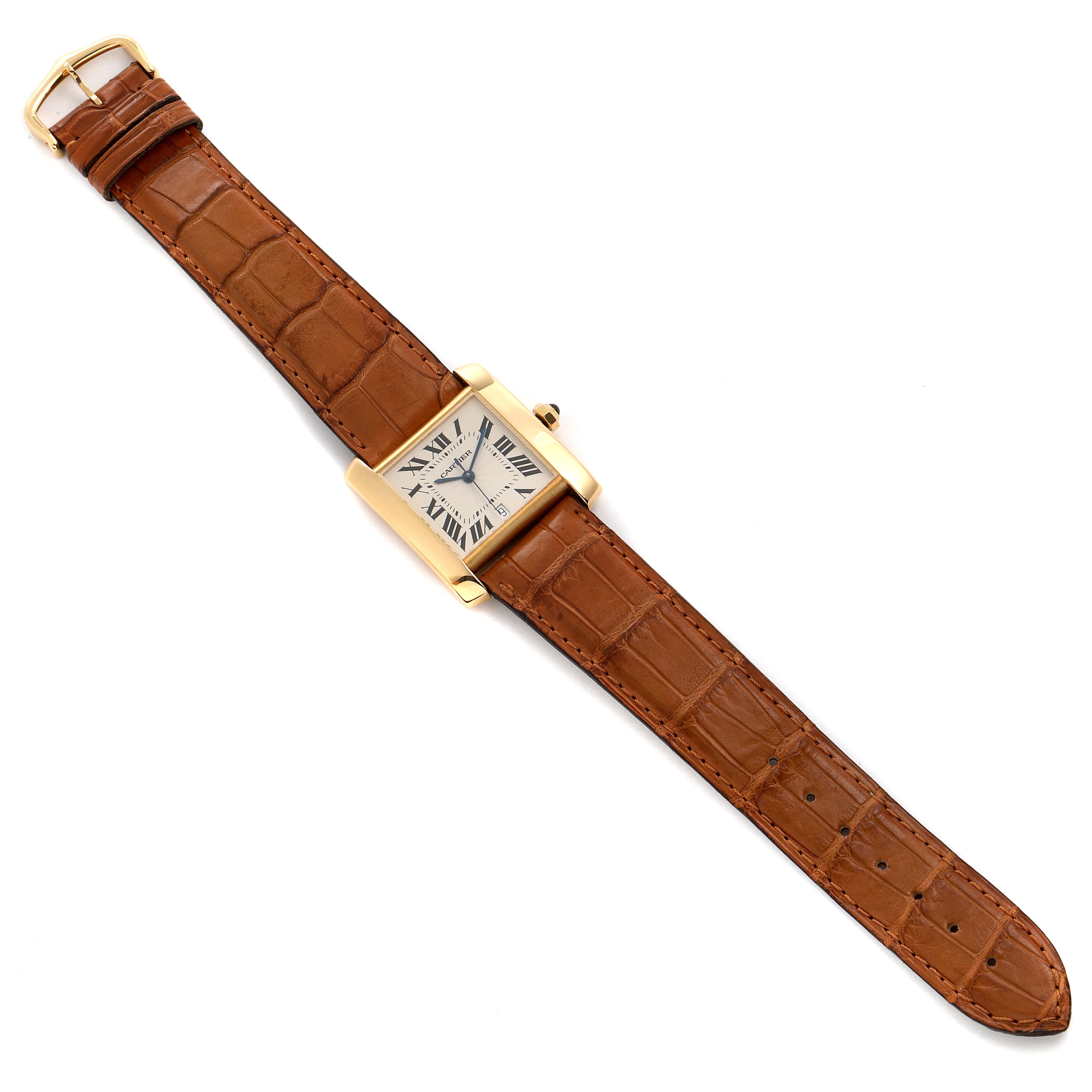 The Cartier Tank Française watch is shown laid flat from a top-down angle, displaying the face and brown leather strap.