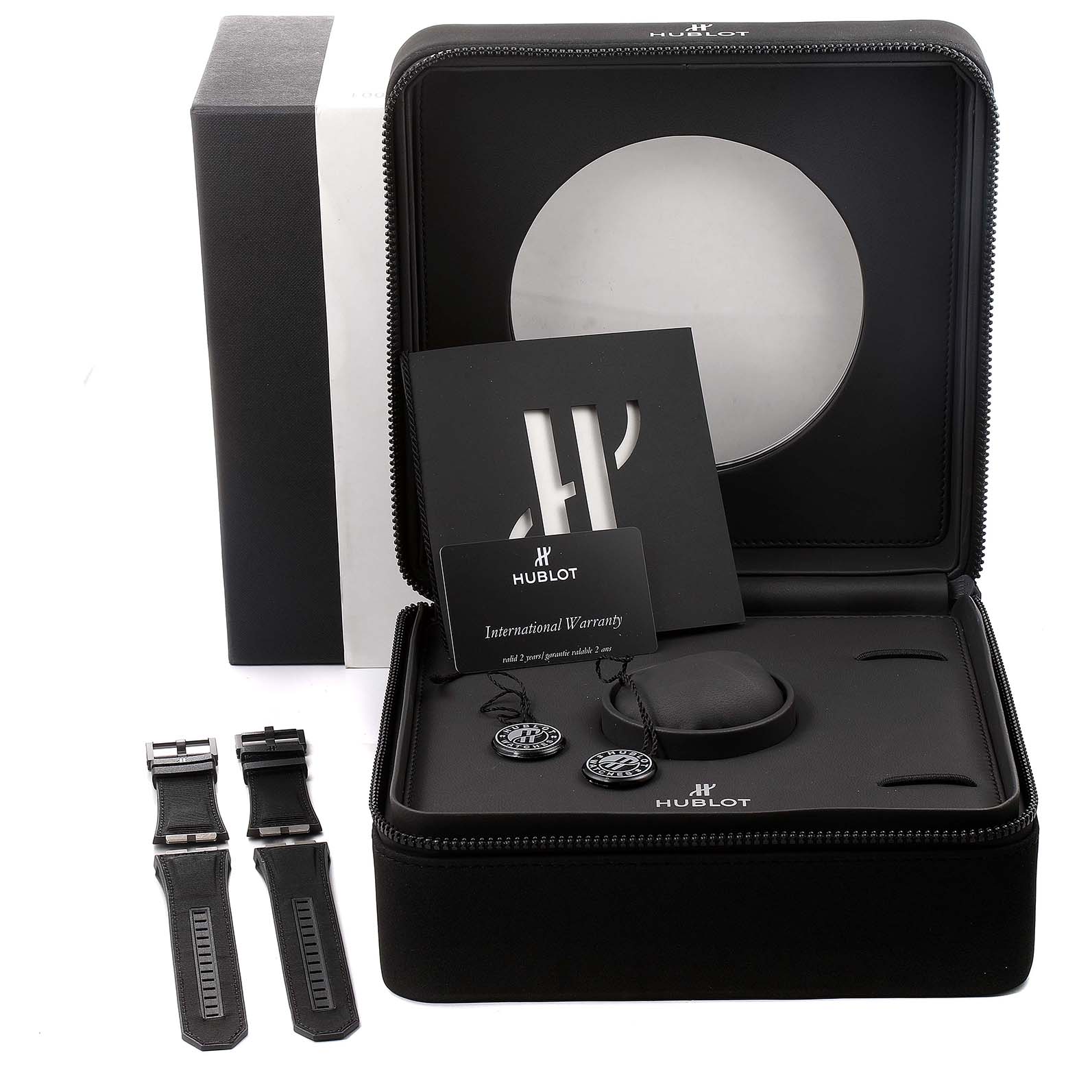 The image shows a Hublot Big Bang 731.QX.1140.RX Men's Titanium Black Dial 731.QX.1140.RX Men's Titanium Black Dial watch case with accessories, including extra straps and an international warranty card.