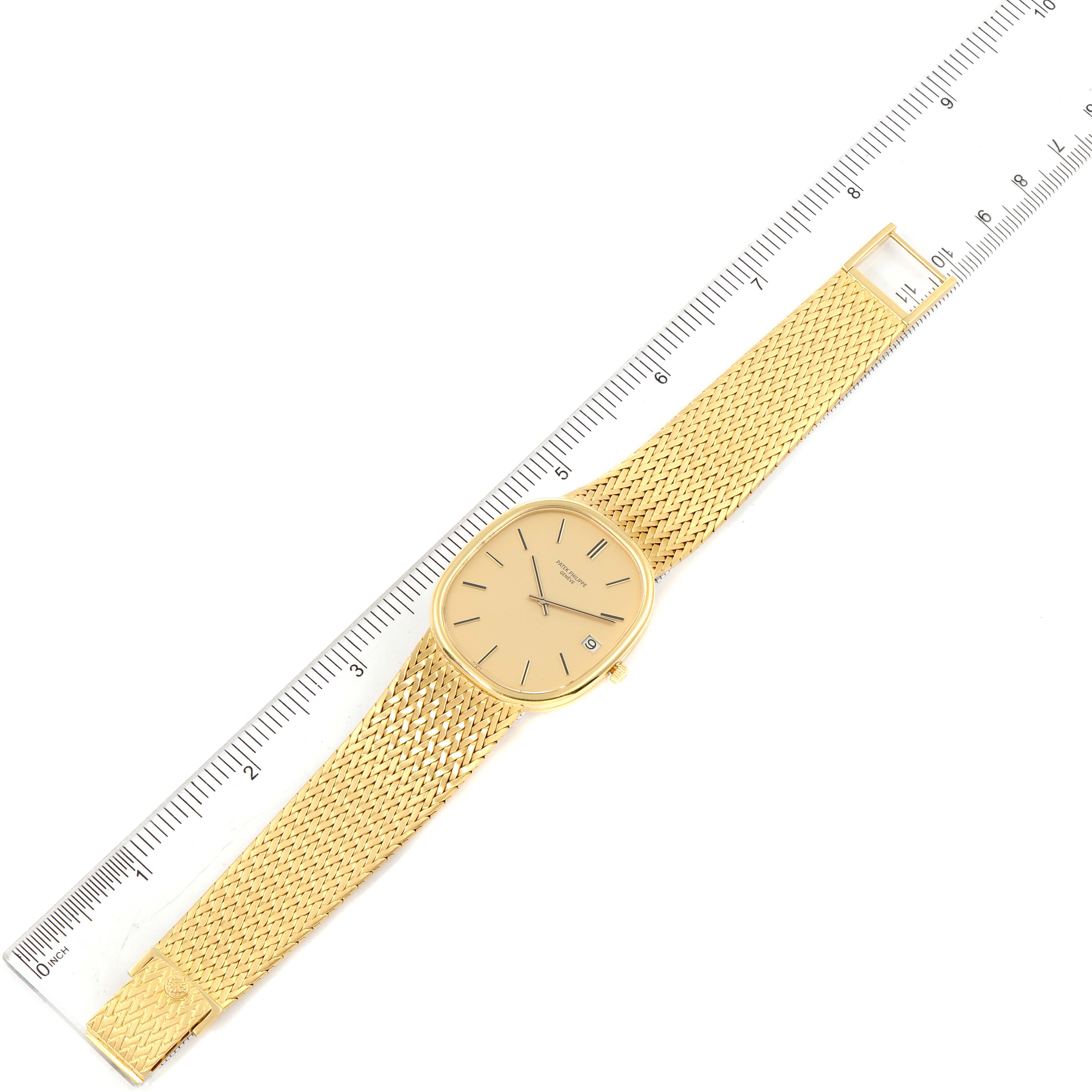 The image shows an overhead view of the Patek Philippe Golden Ellipse 3605 Men
s Yellow Gold Champagne Dial 3605 Men
s Yellow Gold Champagne Dial watch, including its face and golden mesh strap, placed next to a ruler.