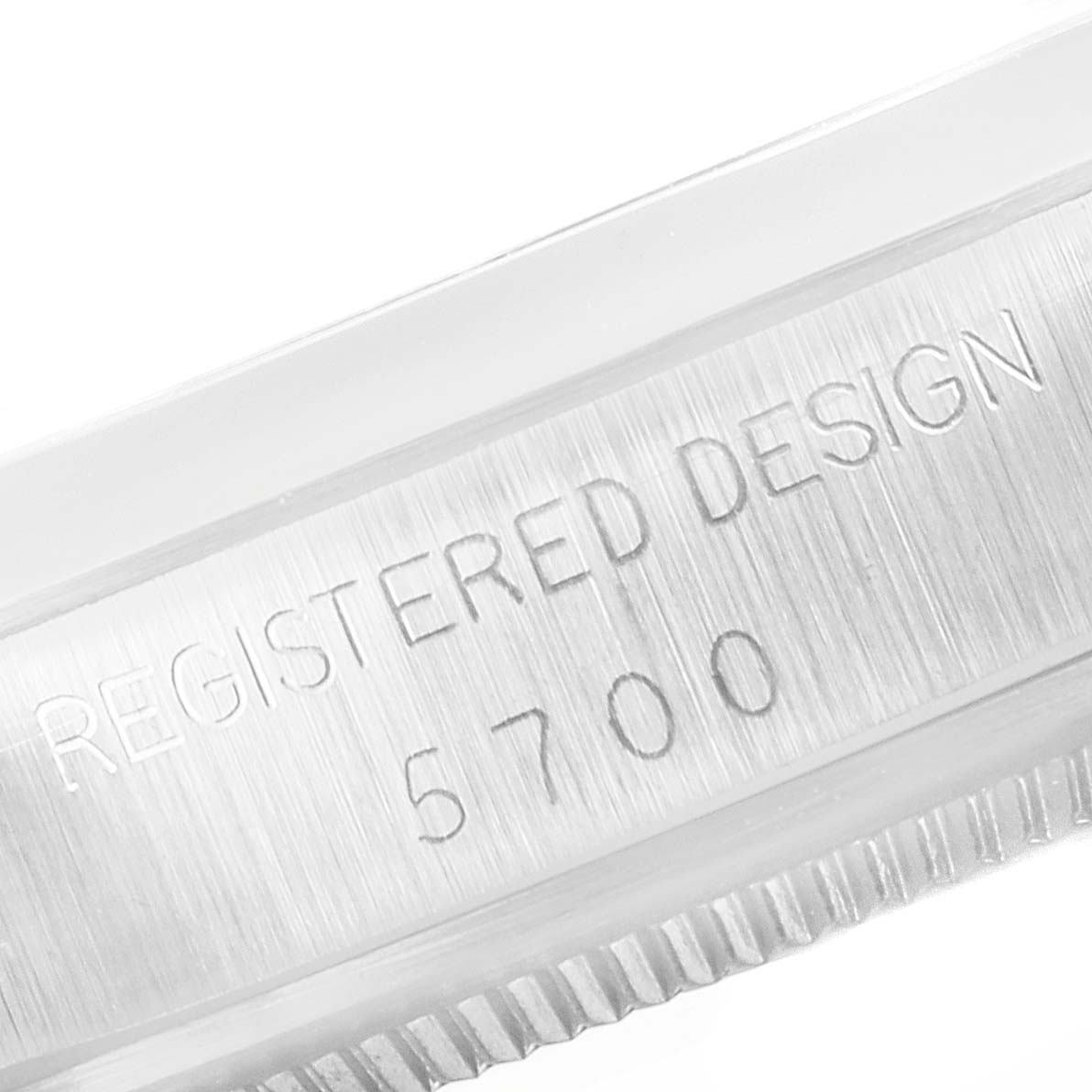 The image shows a close-up of the side of the Rolex Vintage Collection 5700 Men's Stainless Steel Silver Dial 5700 Men's Stainless Steel Silver Dial watch case, focusing on the design engraving "REGISTERED DESIGN 5700."
