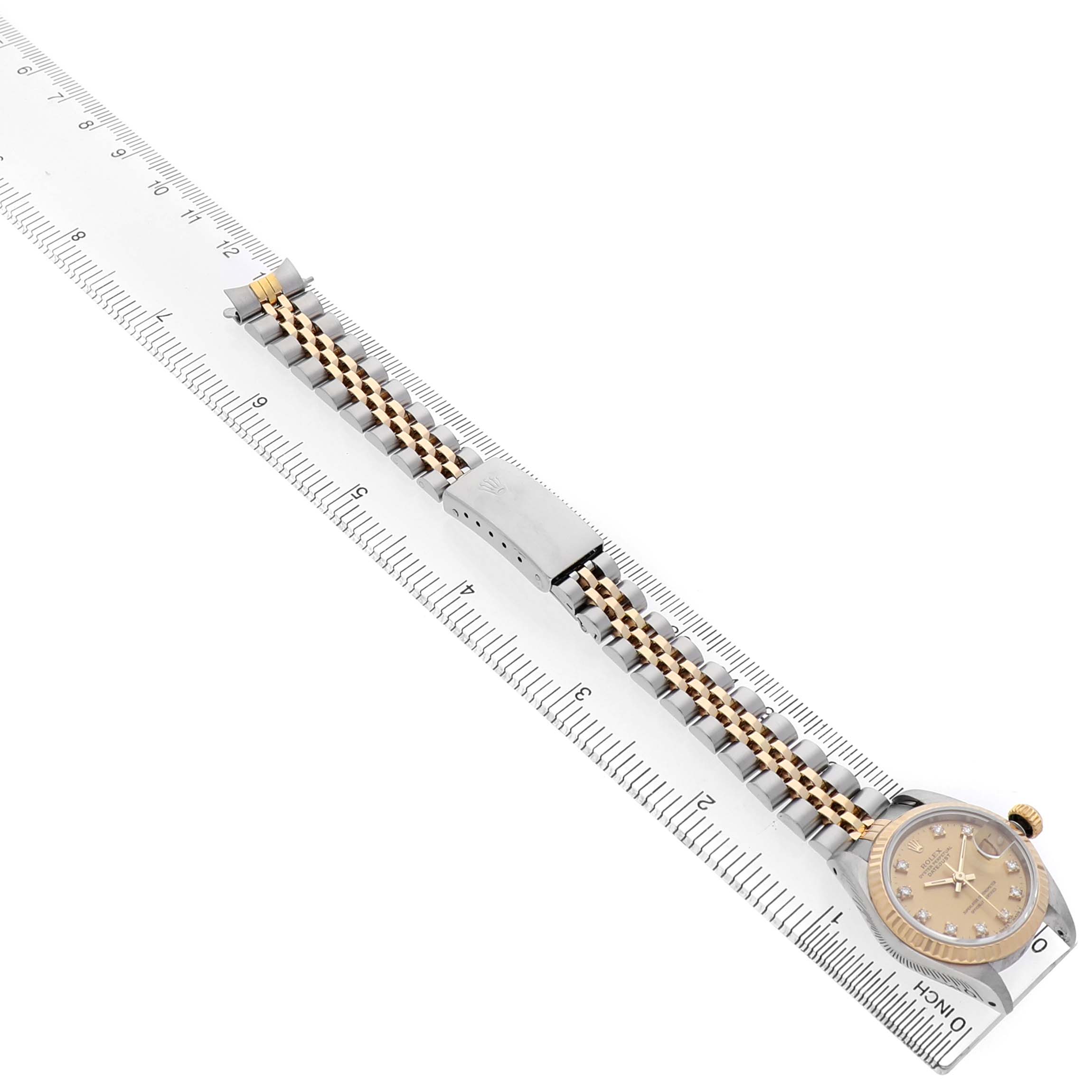 The Rolex Datejust 69173 Women's Steel and Gold (two tone) Champagne Dial watch is shown from an overhead angle, highlighting the face, bracelet, and clasp on a ruler for scale.
