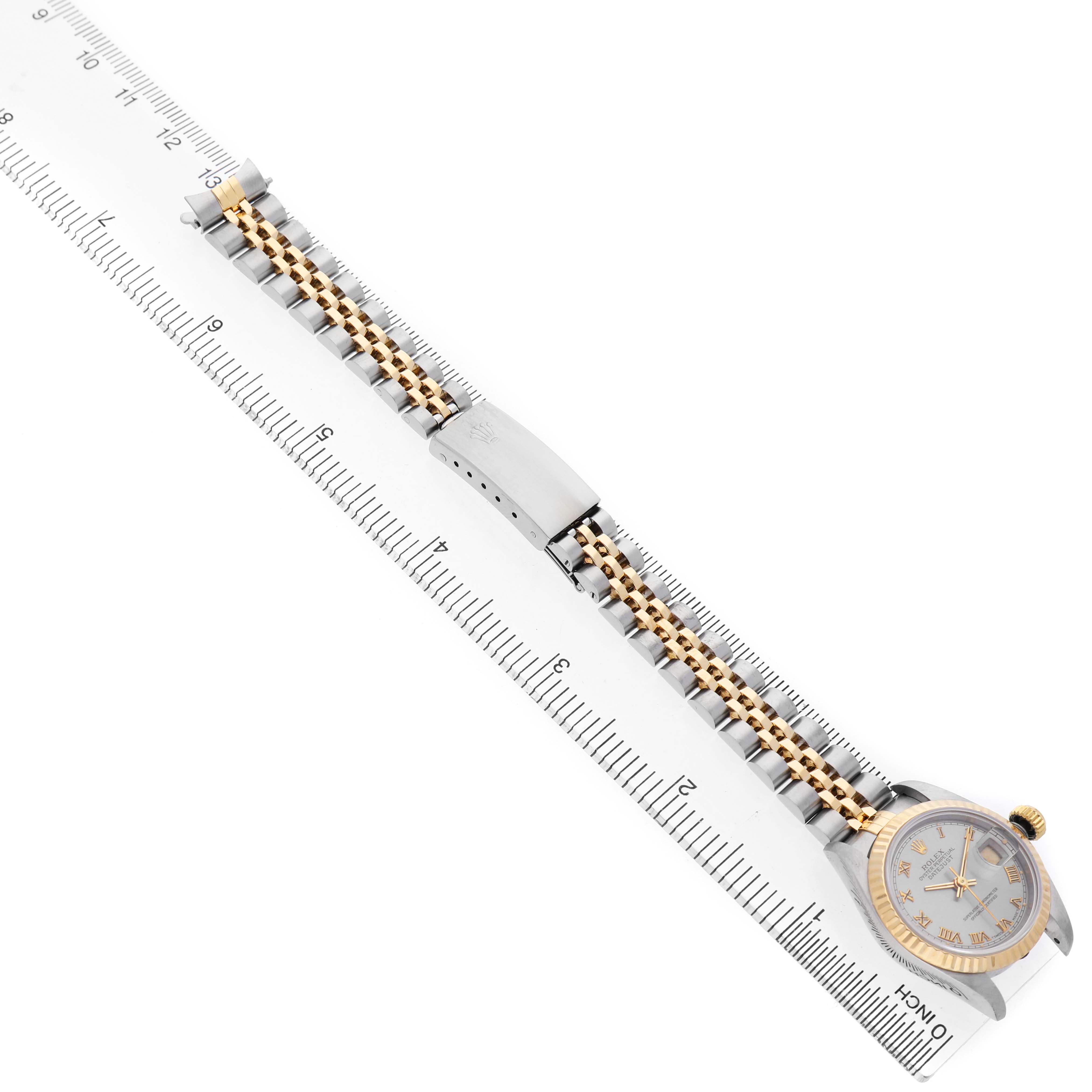 The image shows a Rolex Datejust 69173 Women's Steel and Gold (two tone) Silver Dial watch from a top-down angle, highlighting the bracelet, clasp, and dial alongside a ruler for scale.