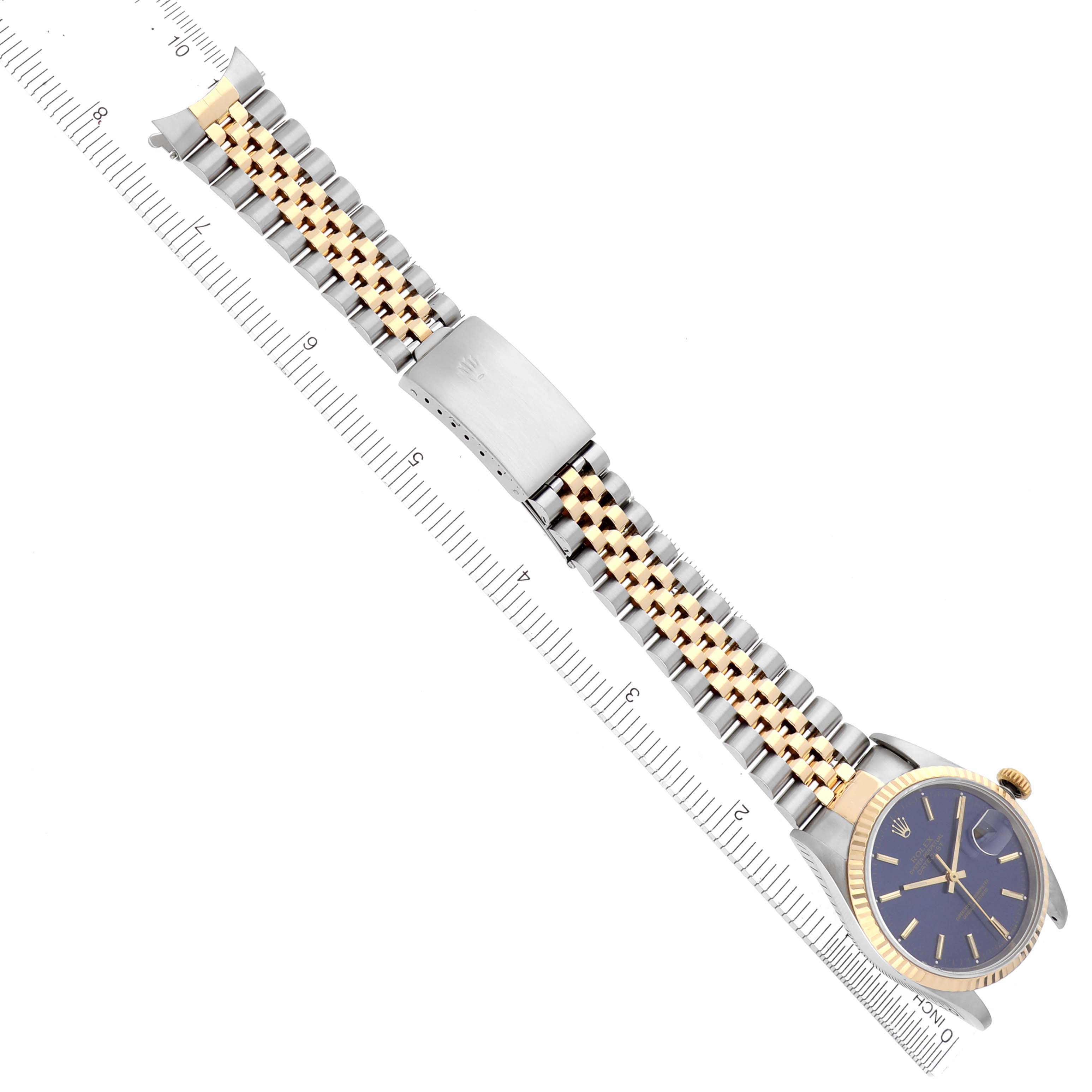The Rolex Datejust 16233 Men's Steel and Gold (two tone) Blue Dial 16233 Men's Steel and Gold (two tone) Blue Dial watch is shown from a top-down angle, featuring the face, crown, and full metal bracelet aligned with a ruler.